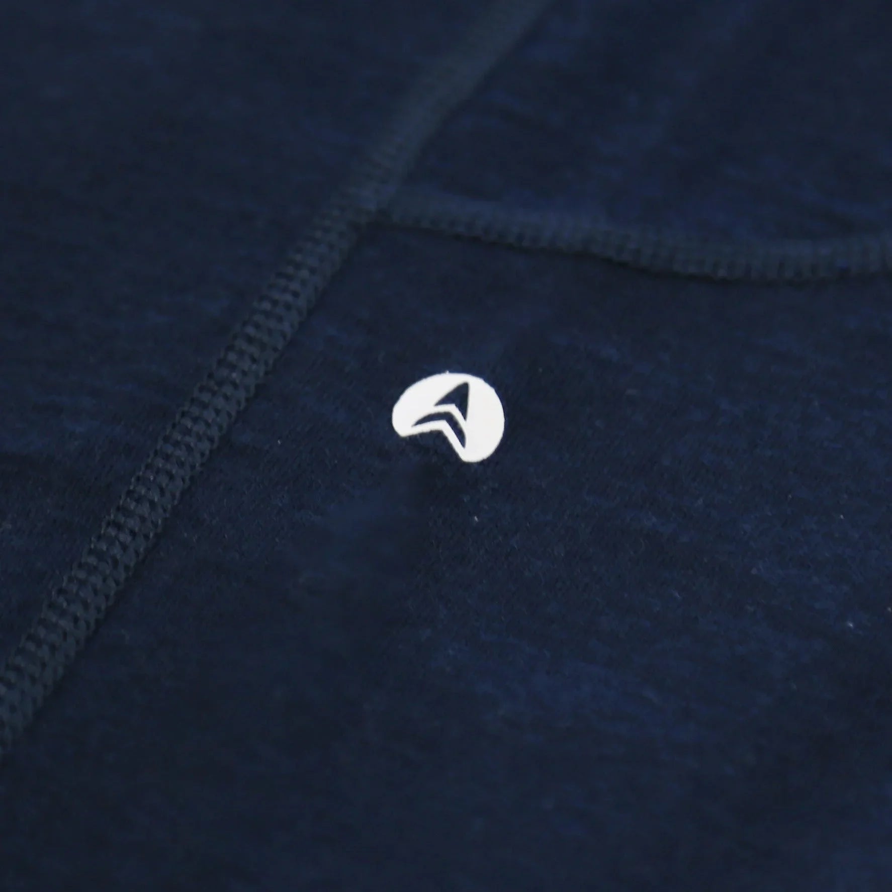Minimalist white arrow logo on dark blue fabric background with stitched seam detail