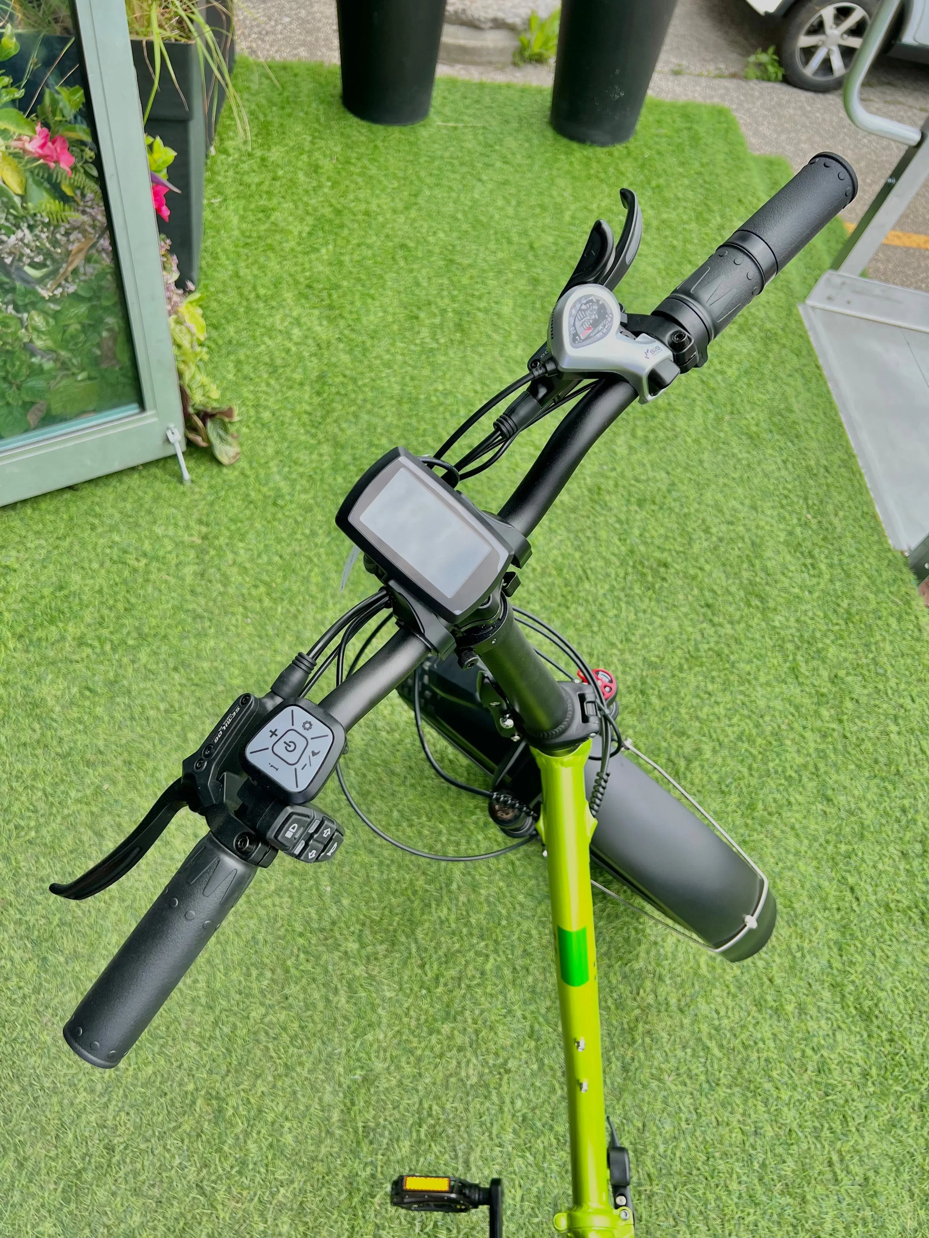 Electric bike handlebars with digital display on green grass outdoors