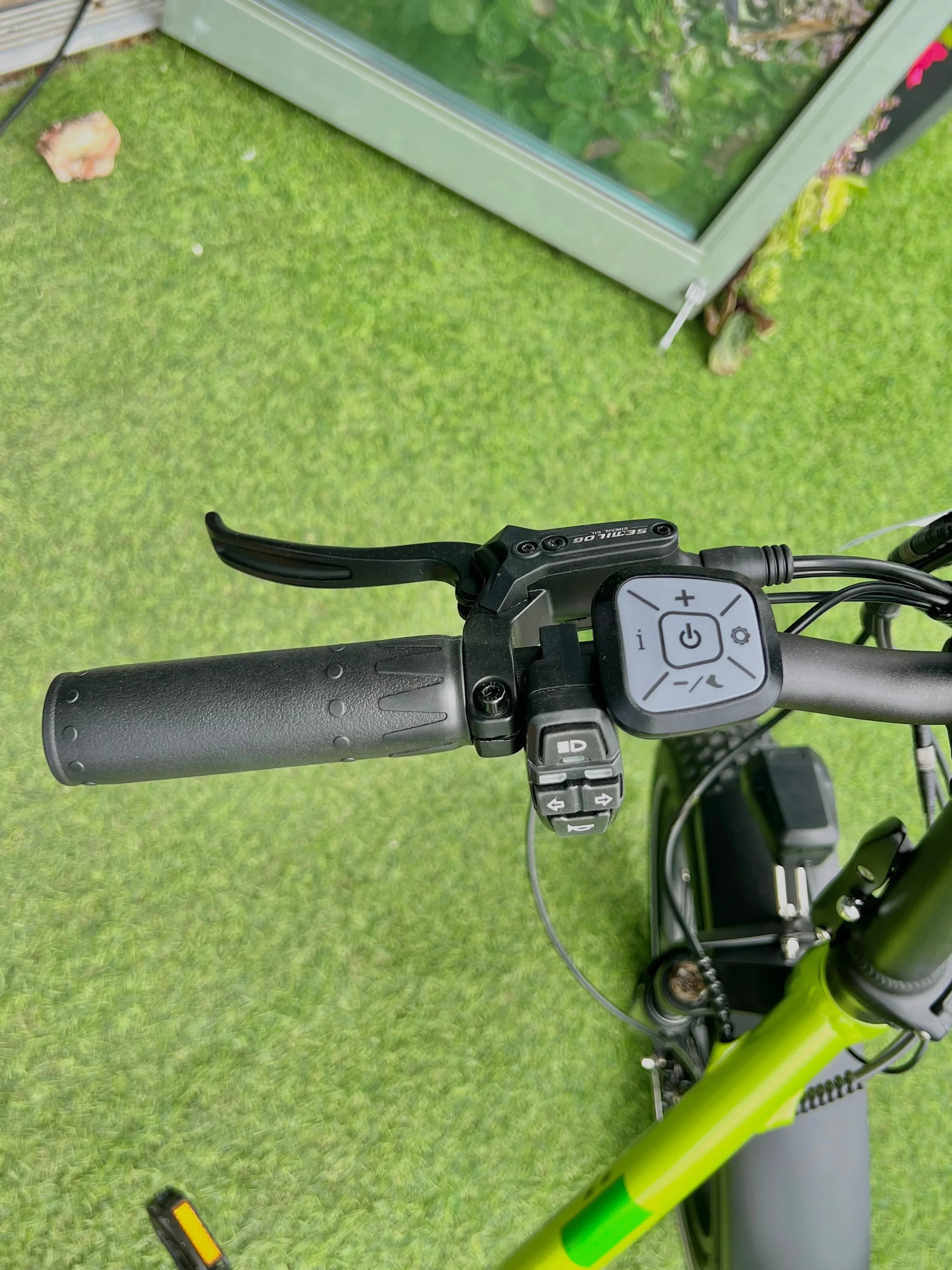 Electric bike handlebar with control panel and grip on green grass