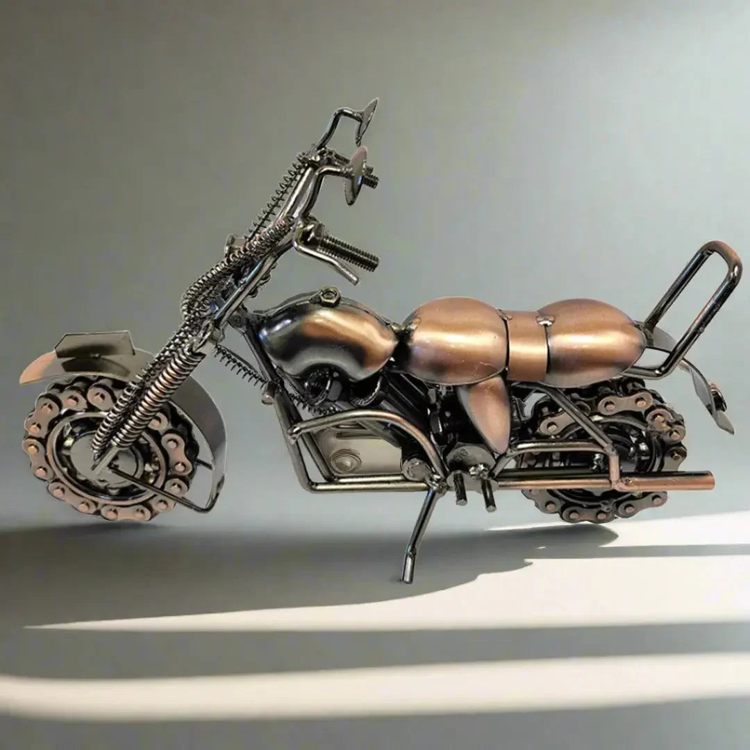 Metal motorcycle model with chain wheels and bronze finish on a neutral background