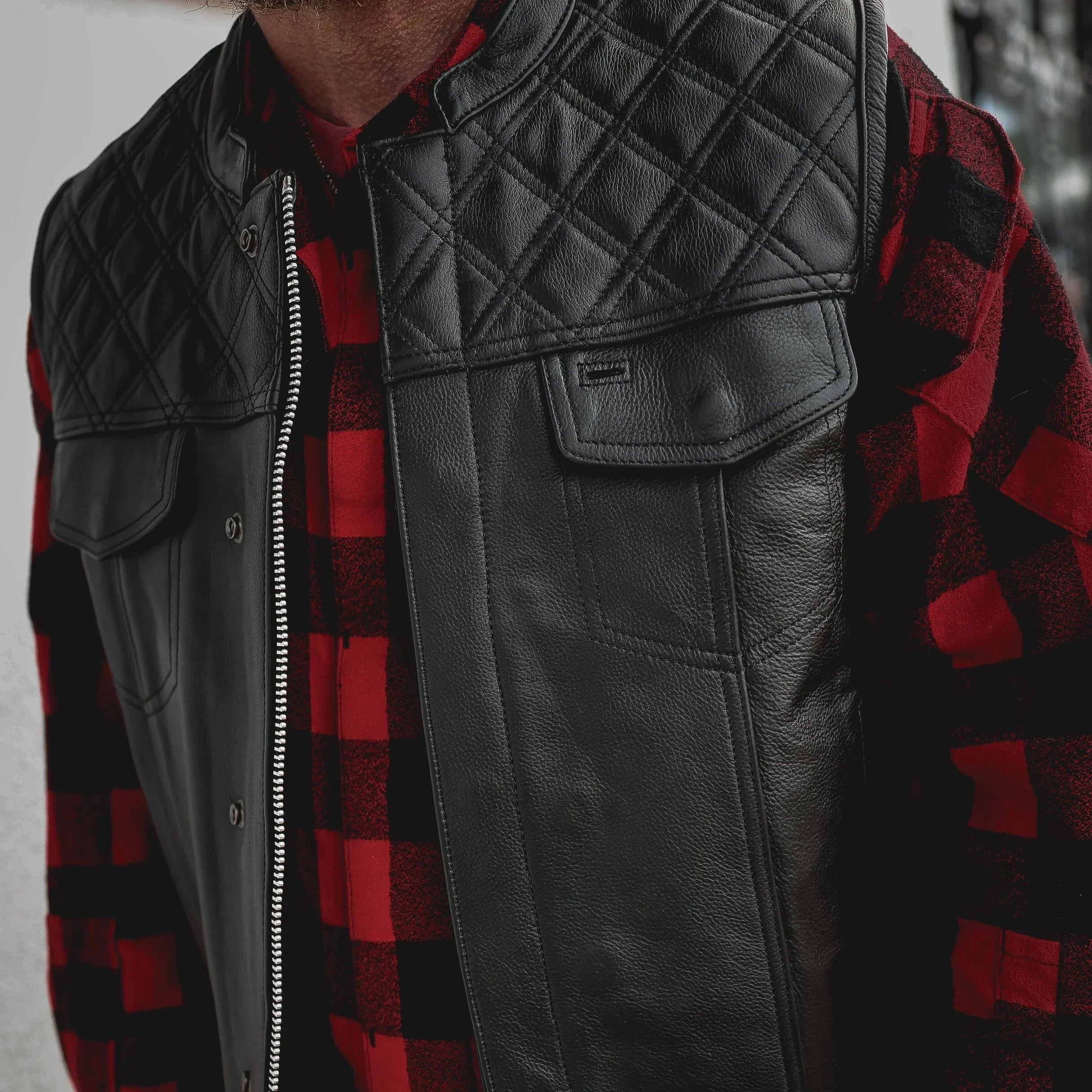 Men's black leather diamond stitch club vest over red plaid shirt