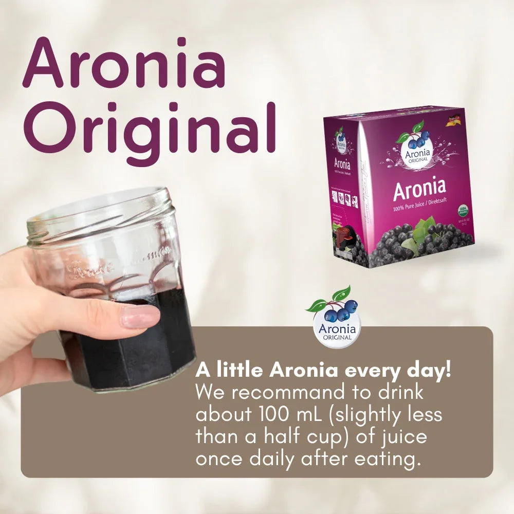 Hand holding glass of dark Aronia juice beside Aronia Original 3-liter juice box