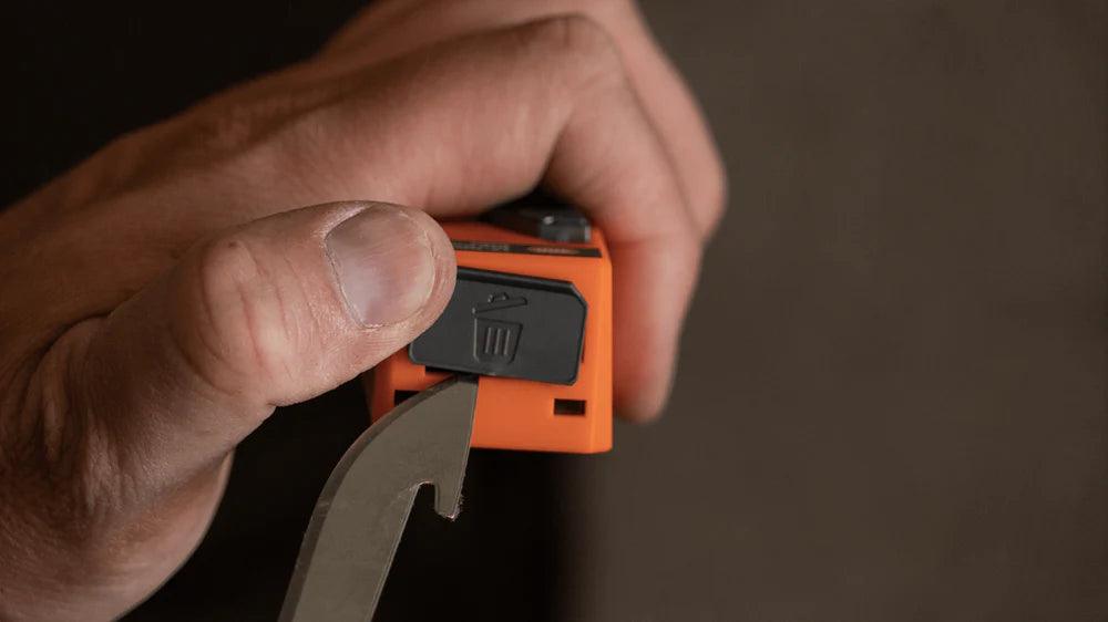 Hand inserting used blade into orange drop-point blade dispenser