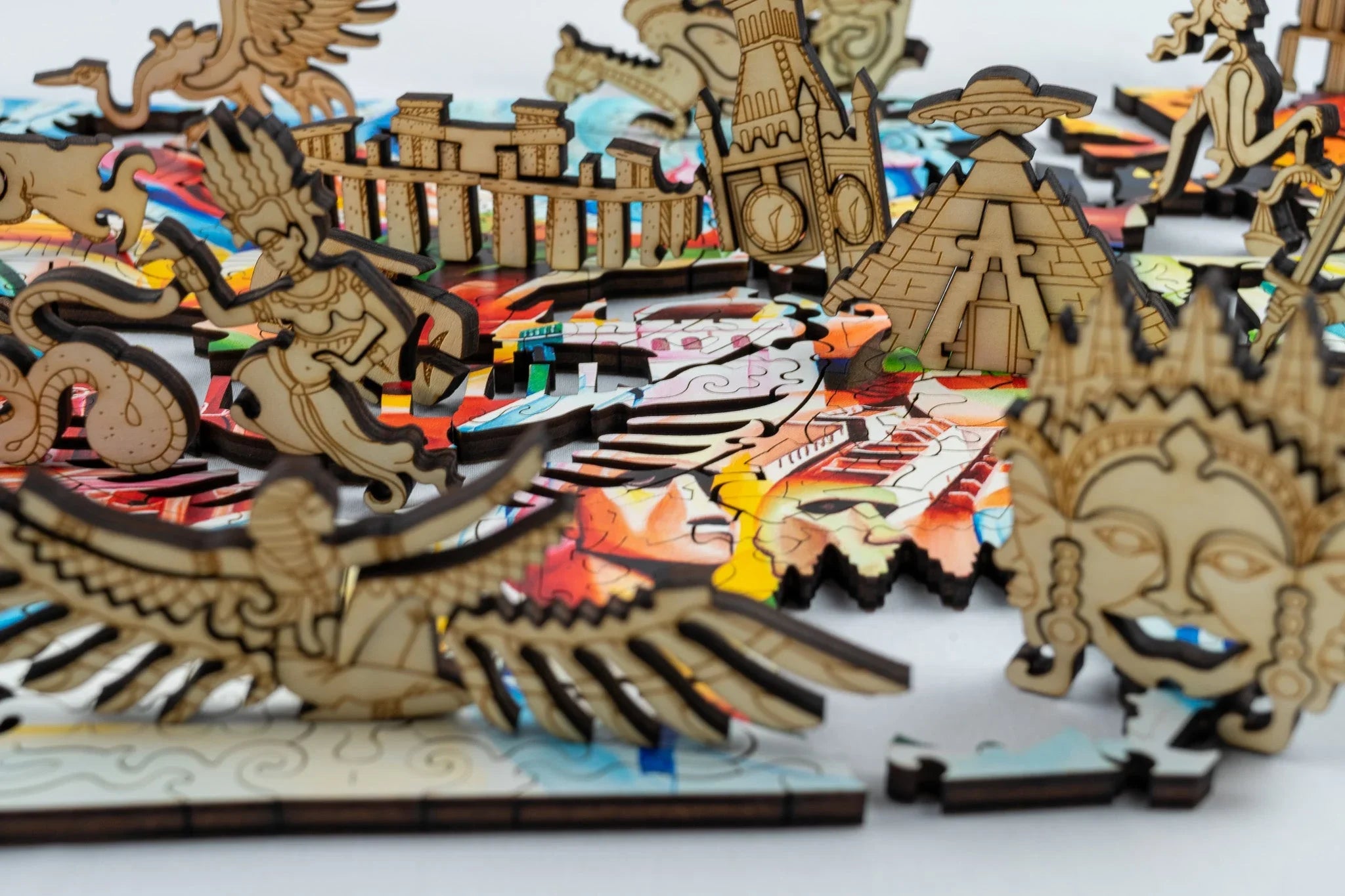 Laser-cut wooden puzzle pieces featuring famous landmarks and mythological figures on a colorful base