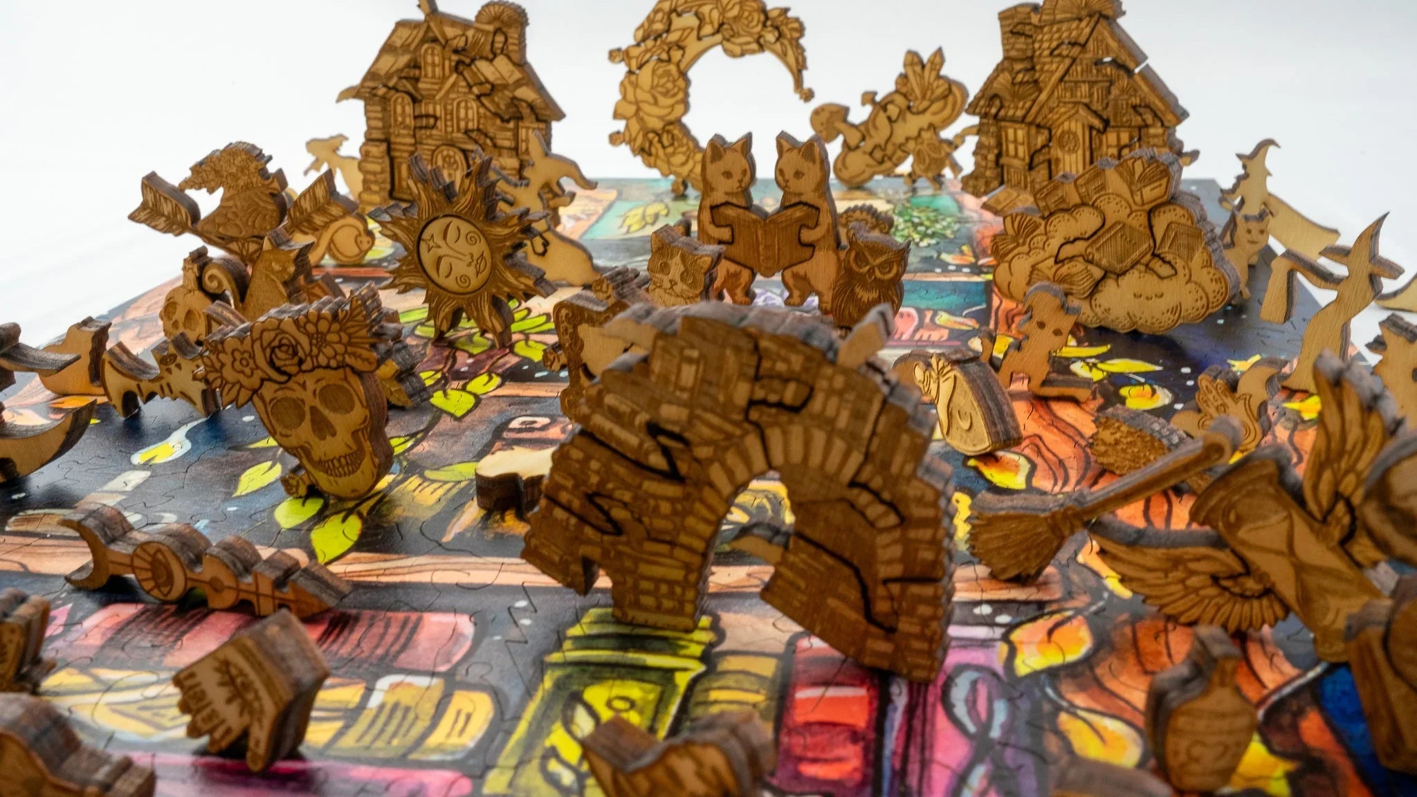 Wooden fantasy puzzle pieces with cats, skull, and houses on a colorful jigsaw board