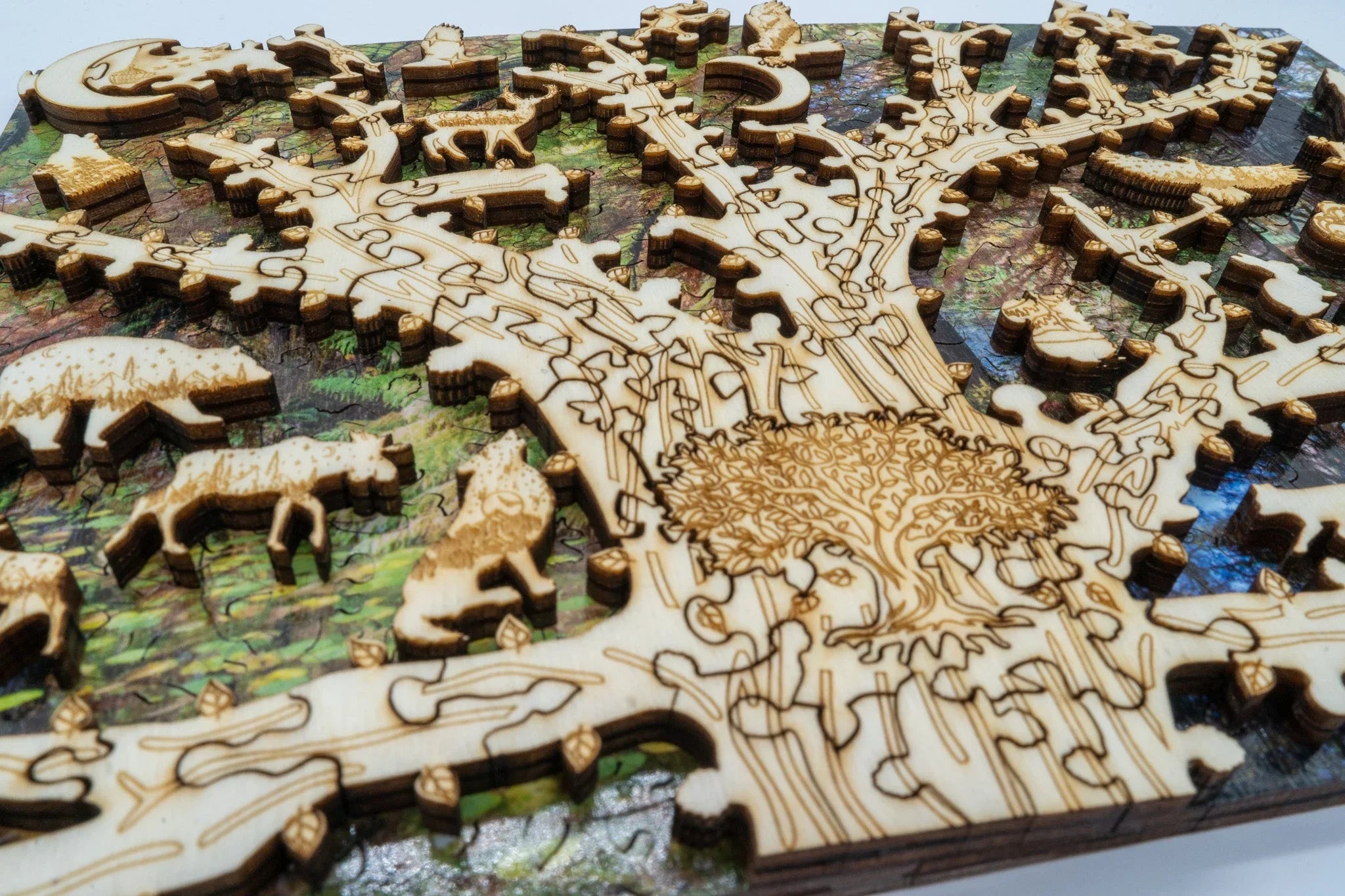 Laser-cut wooden tree puzzle with animal shapes on a colorful forest background