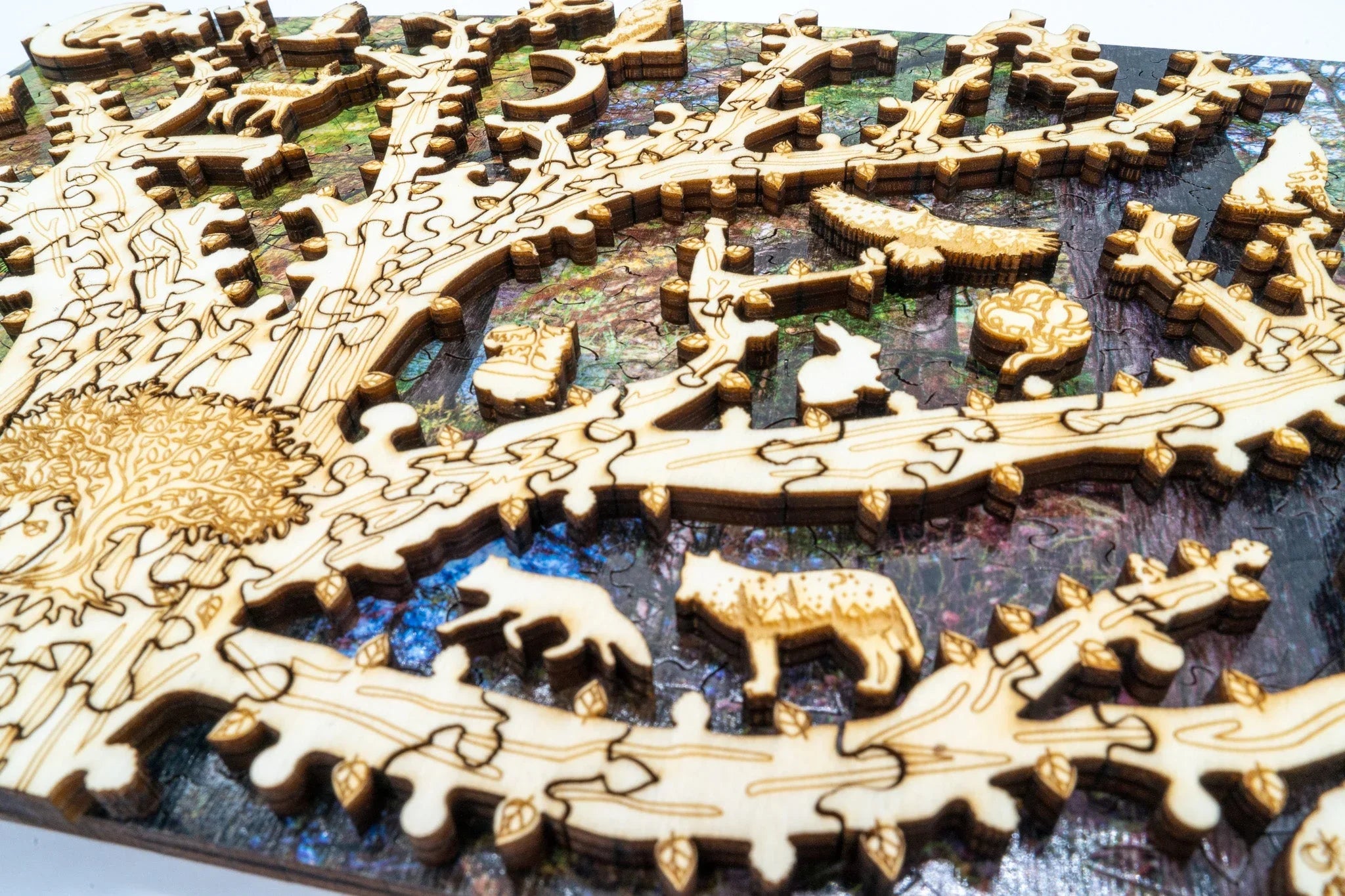 Laser-cut wooden animal puzzle pieces on a colorful tree-themed jigsaw background