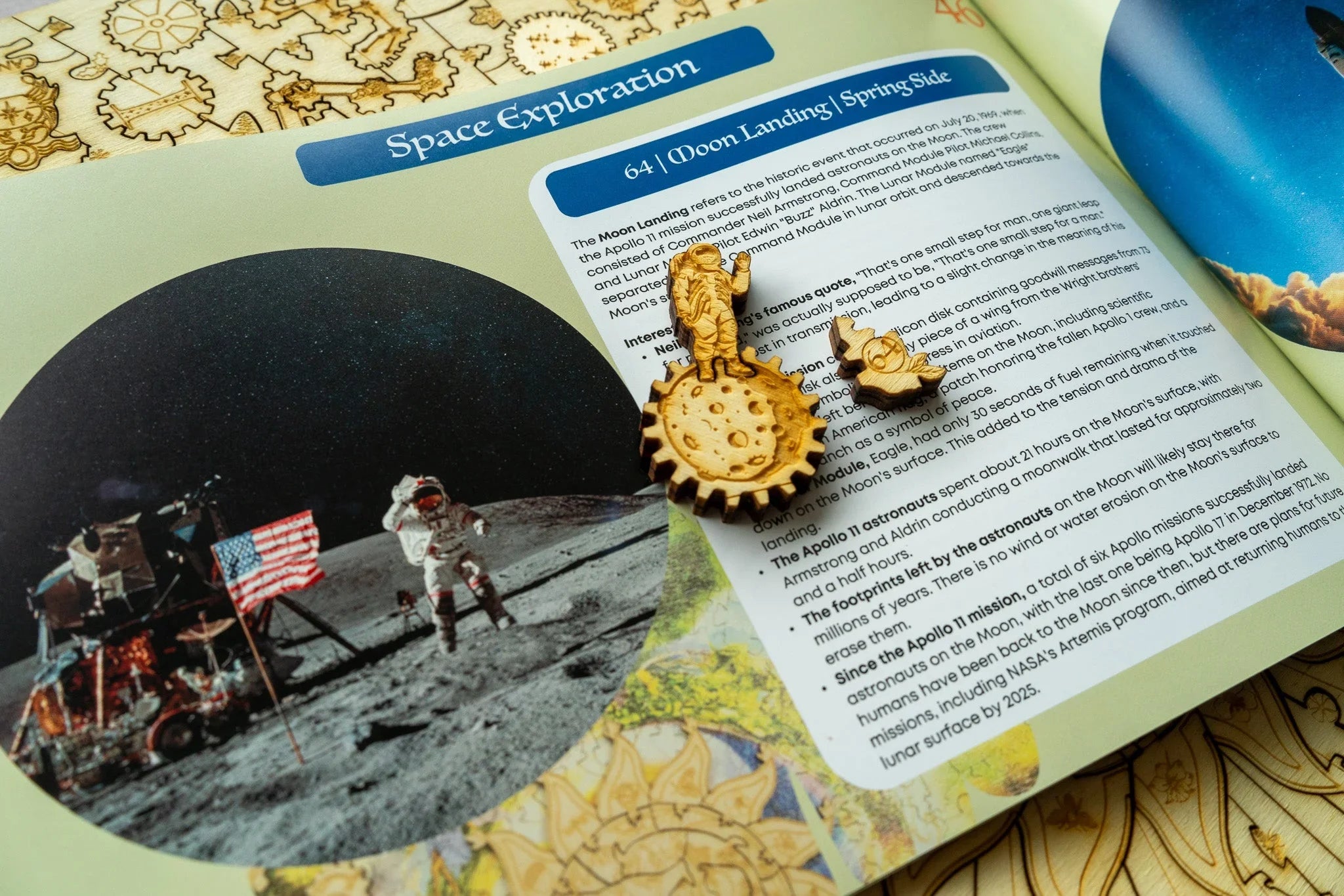 Space exploration book page with moon landing photo, wooden astronaut and rocket figures
