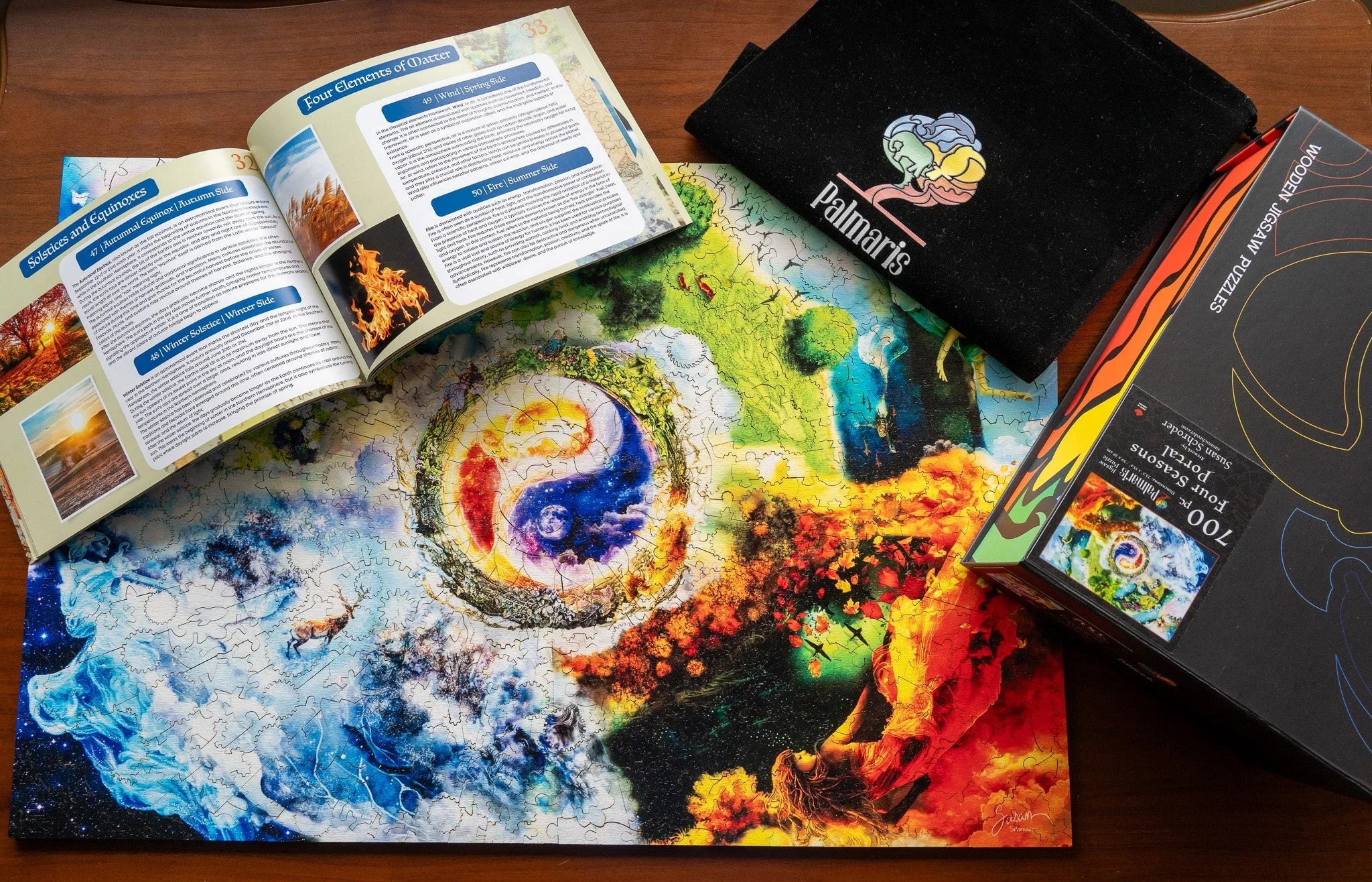 Colorful four seasons jigsaw puzzle completed on table with guidebook, Palmari's pouch, and box