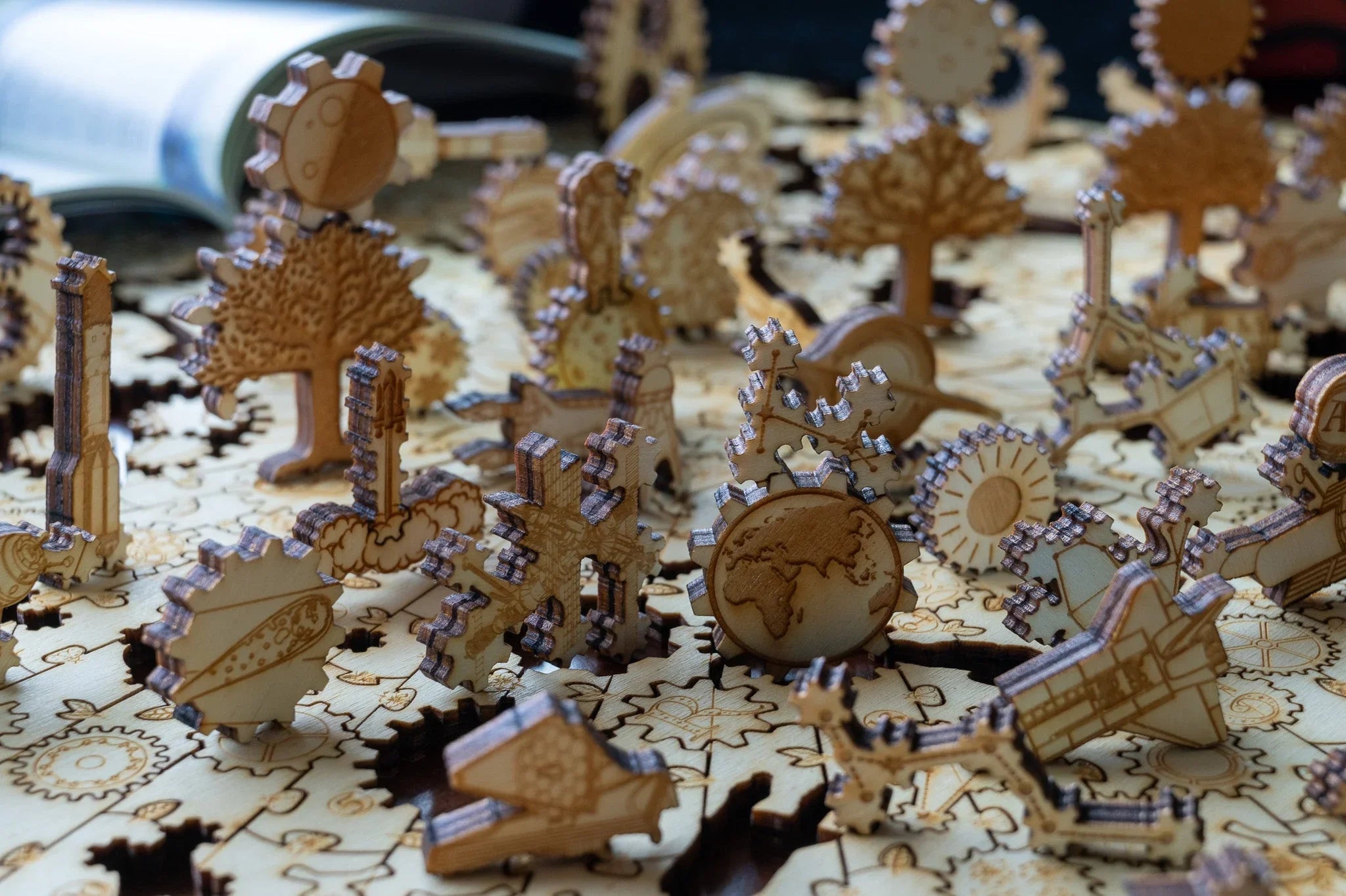 Laser-cut wooden gears and puzzle pieces with engraved designs on a table