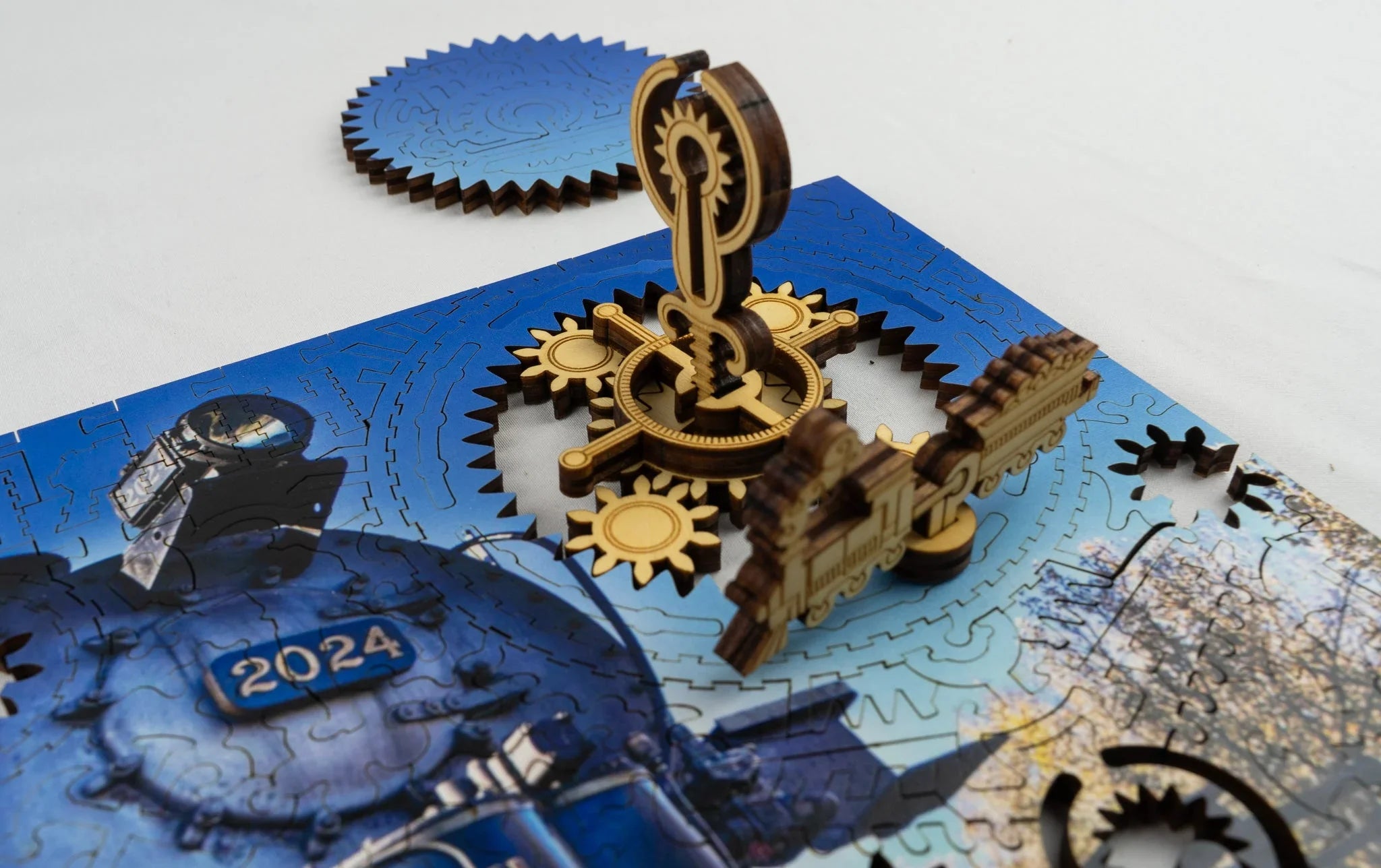 Mechanical wooden train puzzle with gears and blue 2024 locomotive on a white background