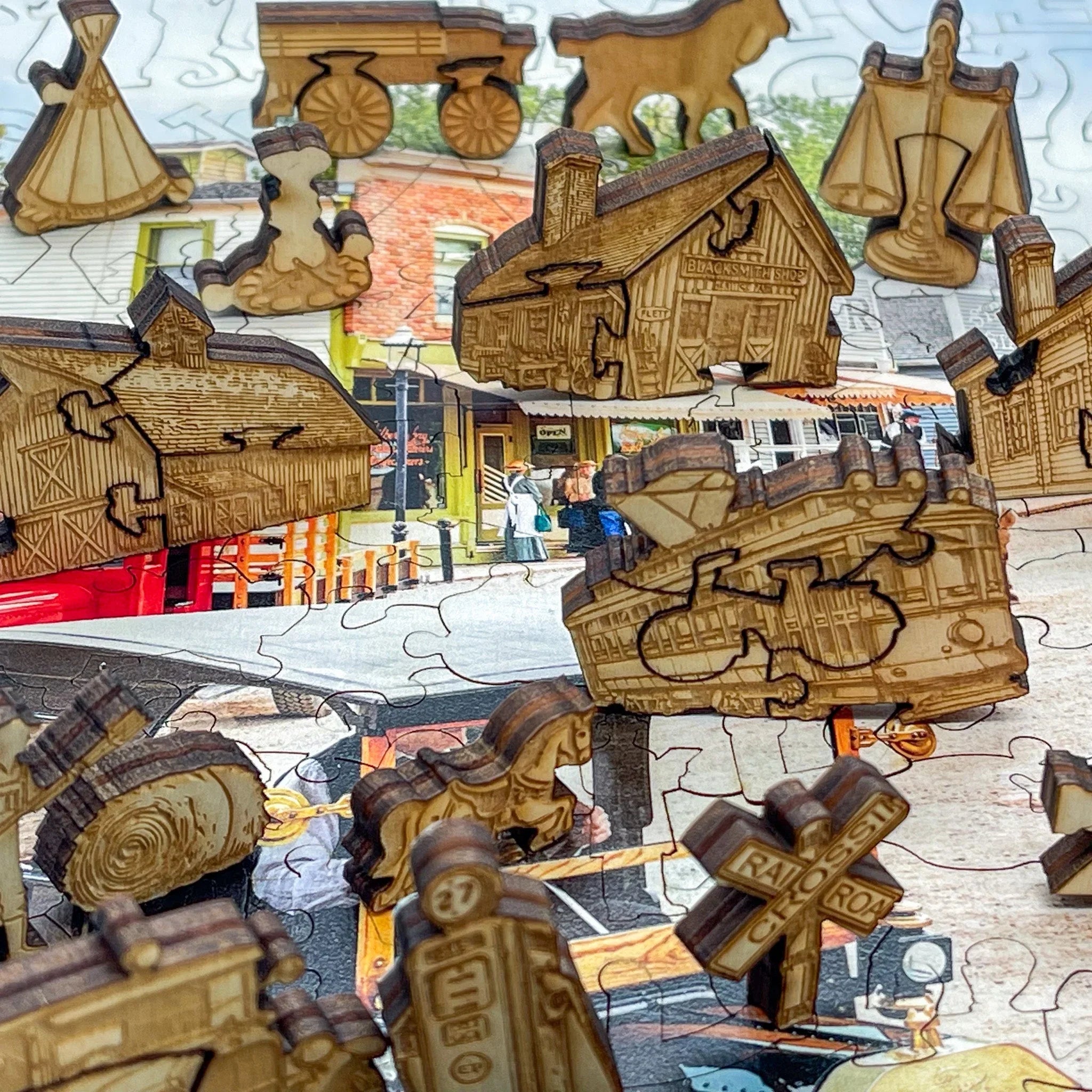 Wooden puzzle pieces shaped as trains, buildings, and signs over a colorful town scene