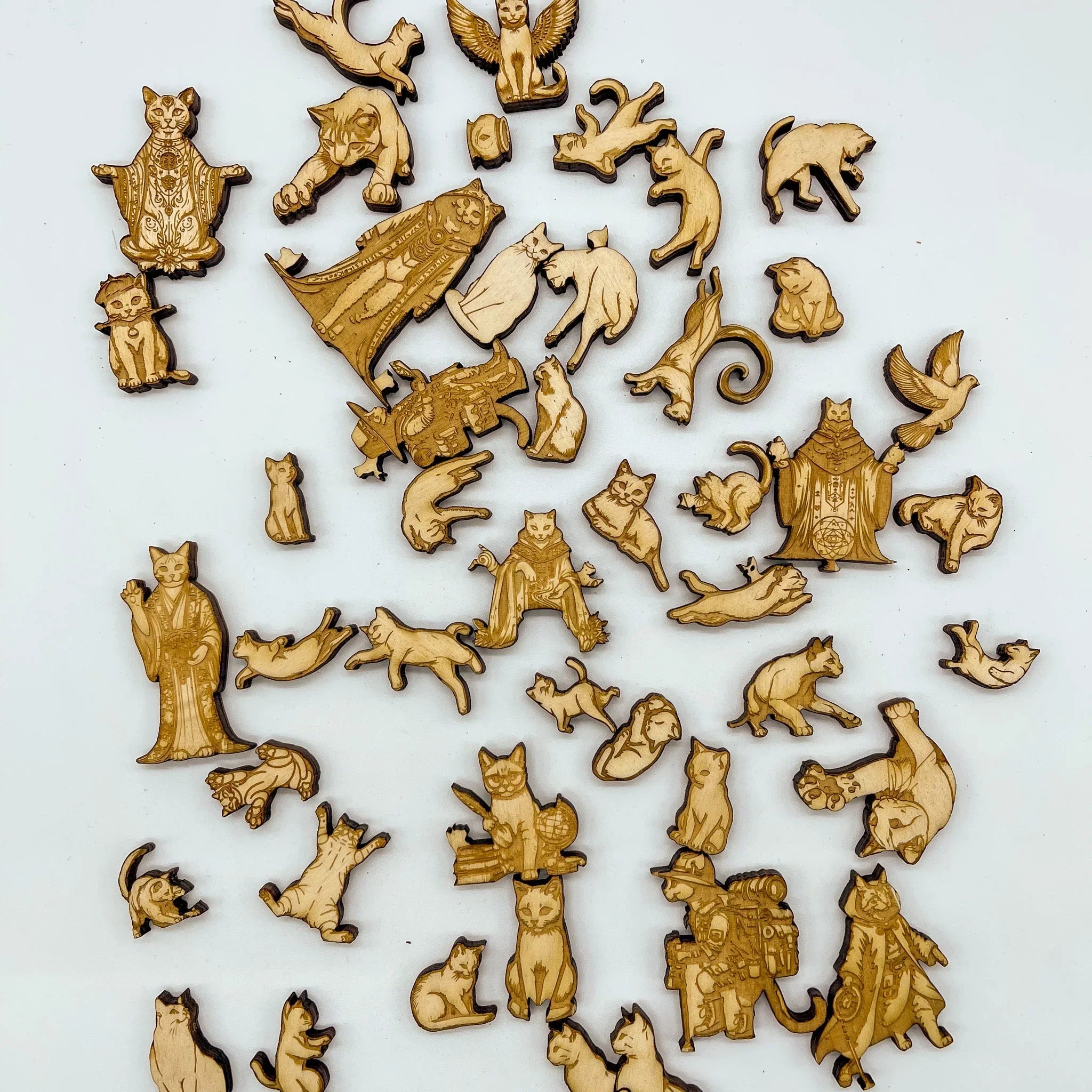 Assorted laser-cut wooden cat puzzle pieces on white background