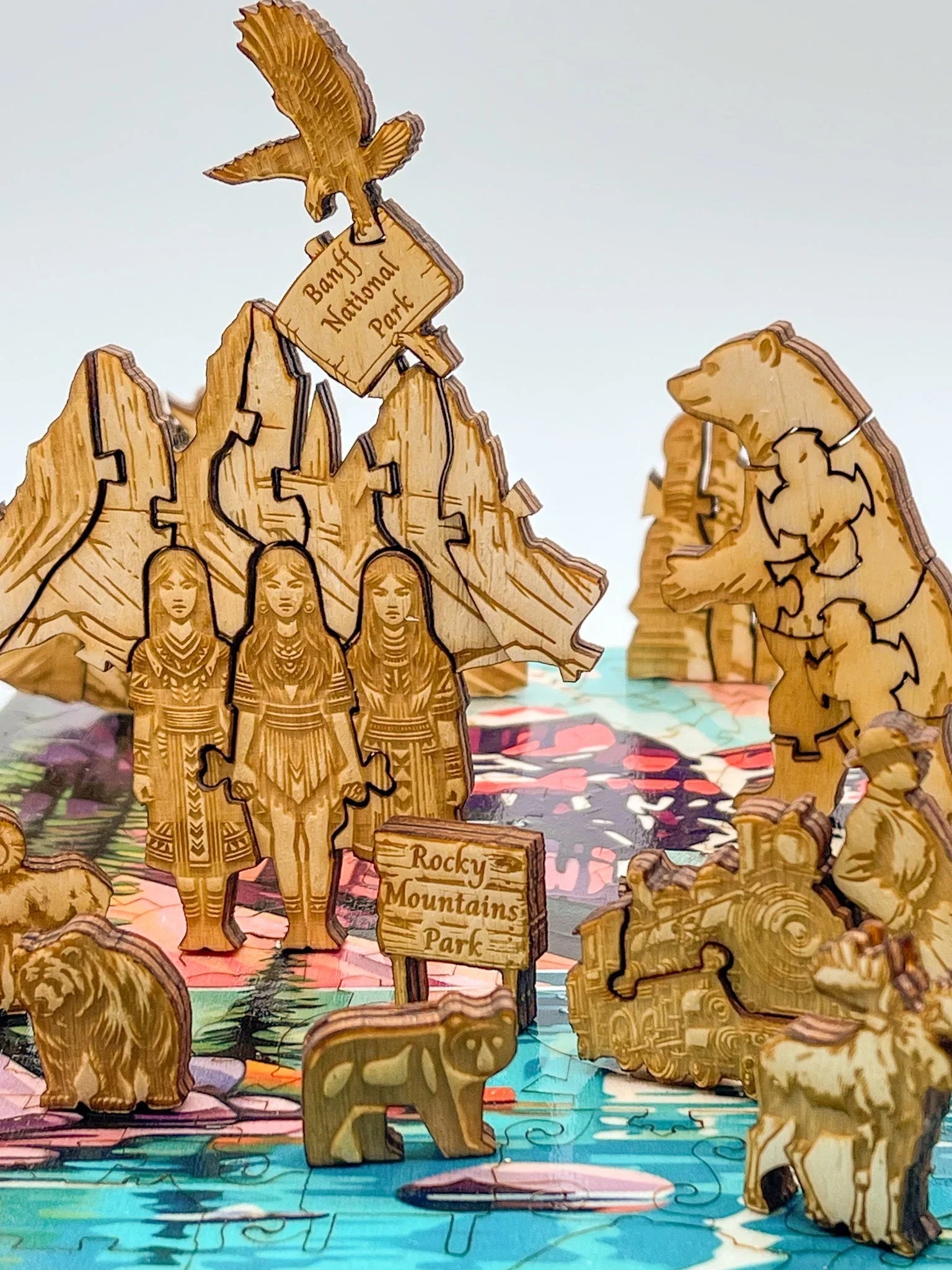 Wooden puzzle pieces of Banff and Rocky Mountains Parks, animals, train, and people on colorful background