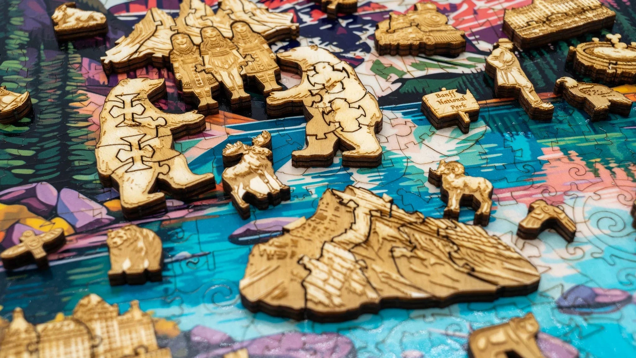Wooden jigsaw puzzle pieces shaped like bears, mountains, and animals on a colorful Canada map