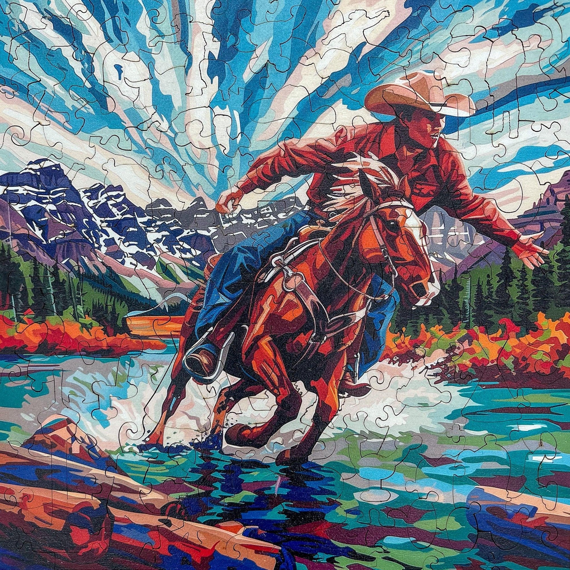Cowboy riding horse across river with mountains, forest, and blue sky puzzle art