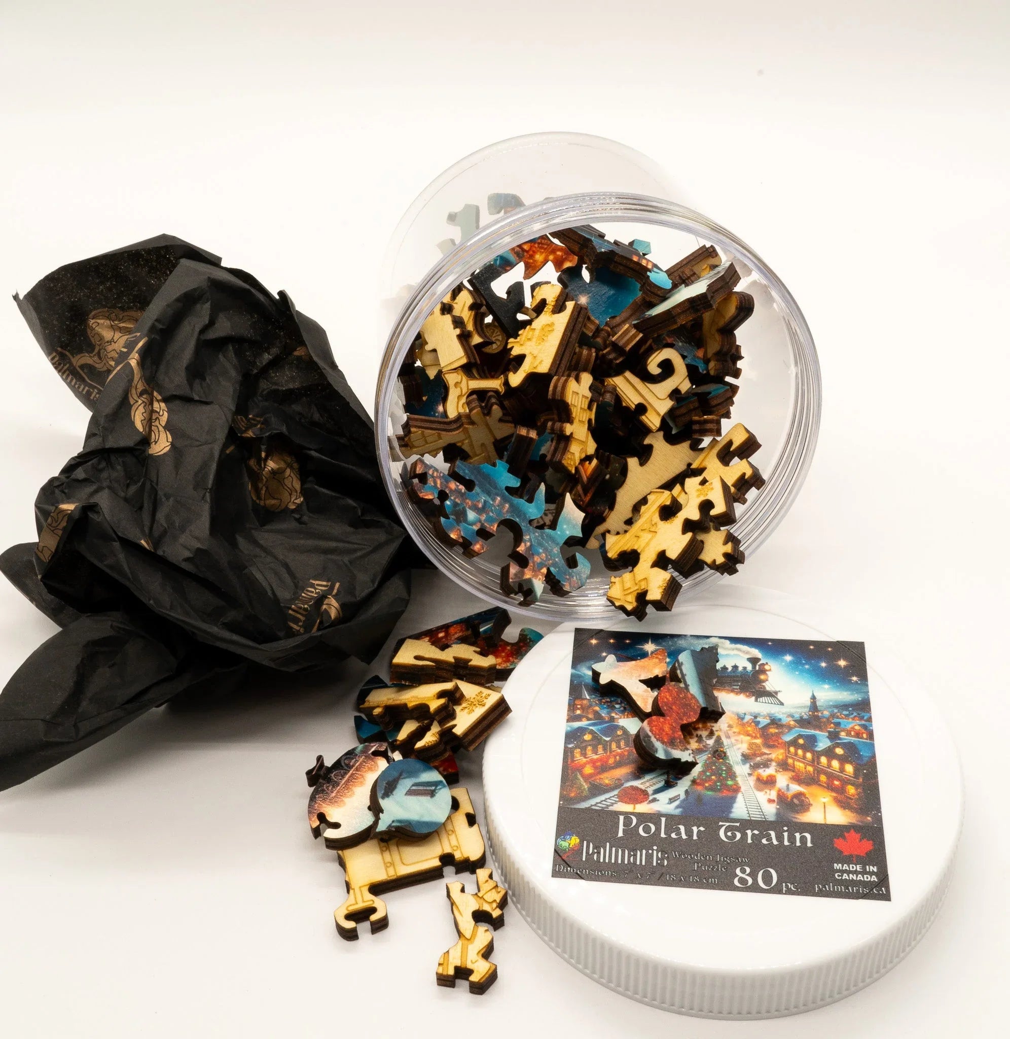 Polar Train wooden jigsaw puzzle pieces in clear jar with illustrated lid and black tissue paper
