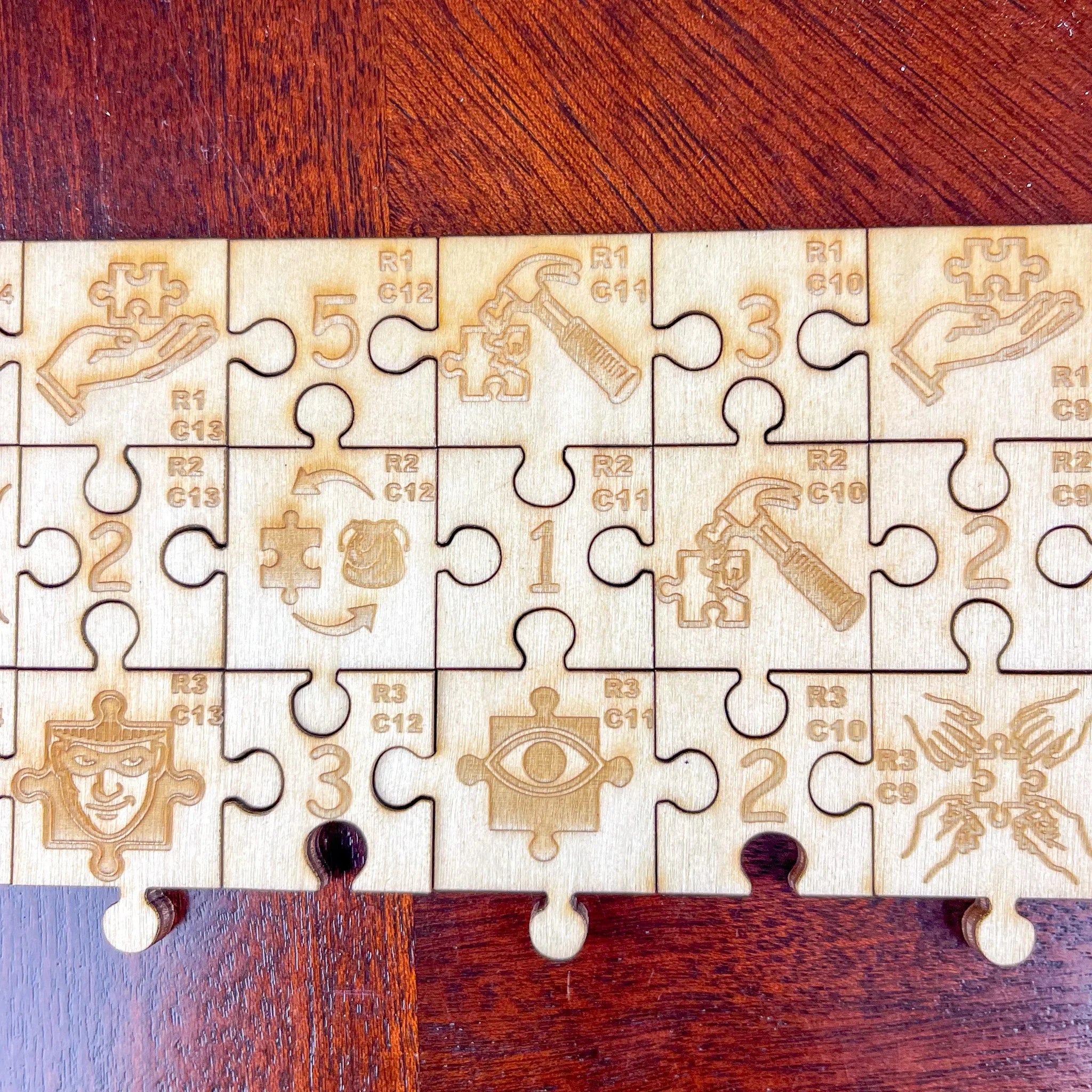 Laser-cut wooden puzzle pieces with engraved icons, numbers, and symbols on wood table