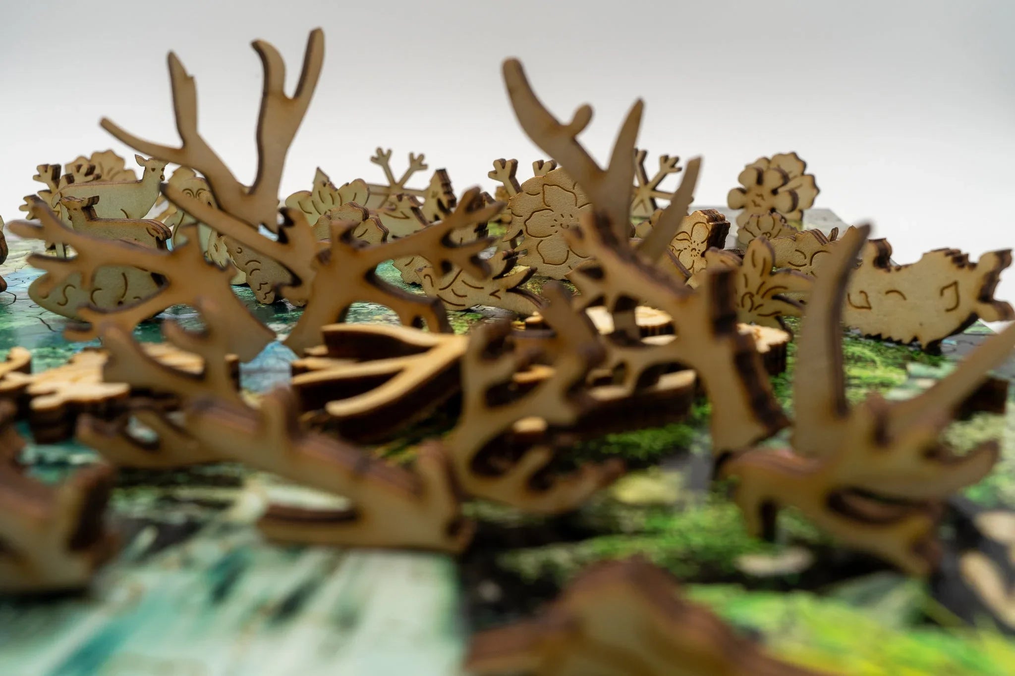 Laser-cut wooden animal and plant pieces on a colorful game board