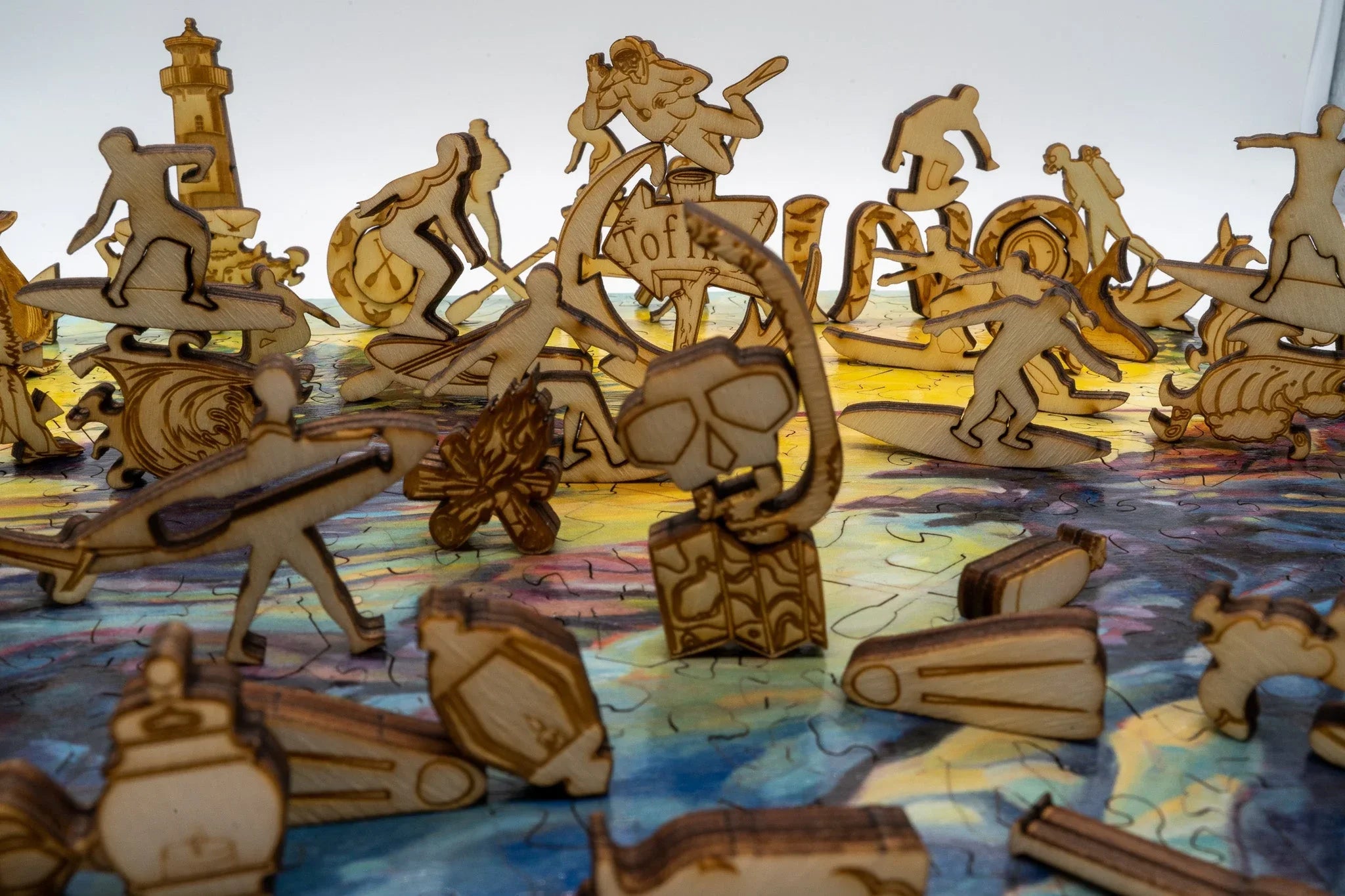 Wooden ocean-themed puzzle pieces with surfers, kayakers, lighthouse, and campfire