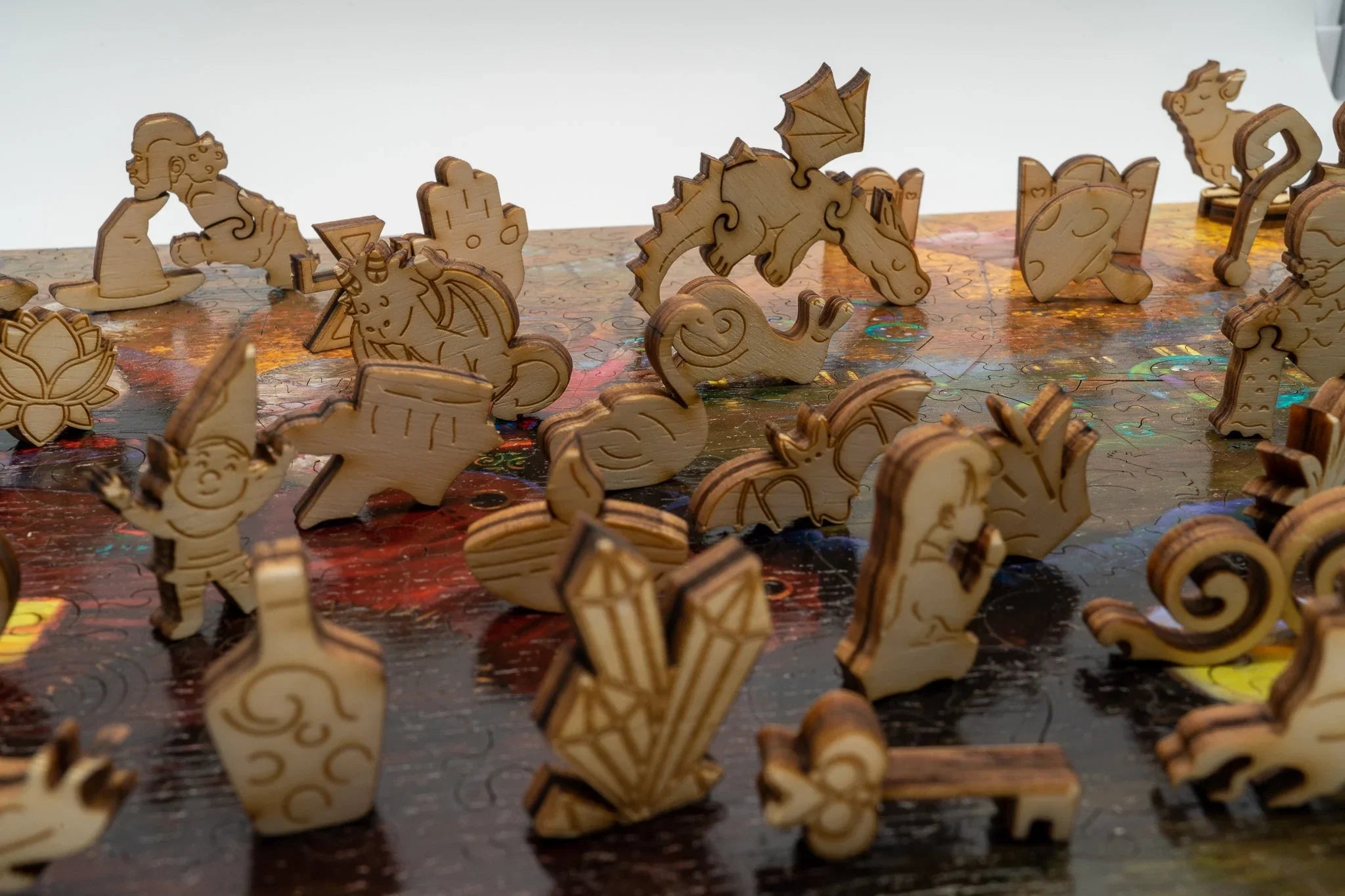 Laser-cut wooden puzzle pieces in whimsical animal and fantasy shapes on a colorful puzzle surface