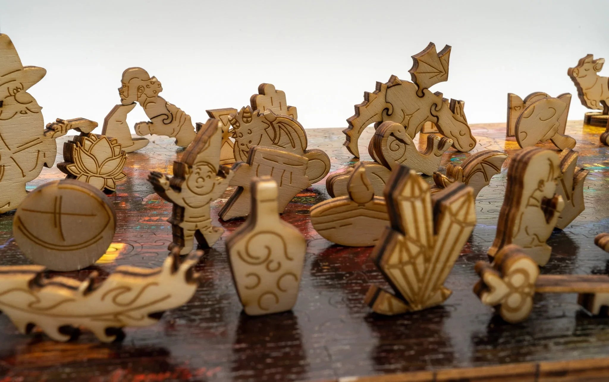 Laser-cut wooden fantasy puzzle pieces including dragon, wizard, and crystal shapes on a table