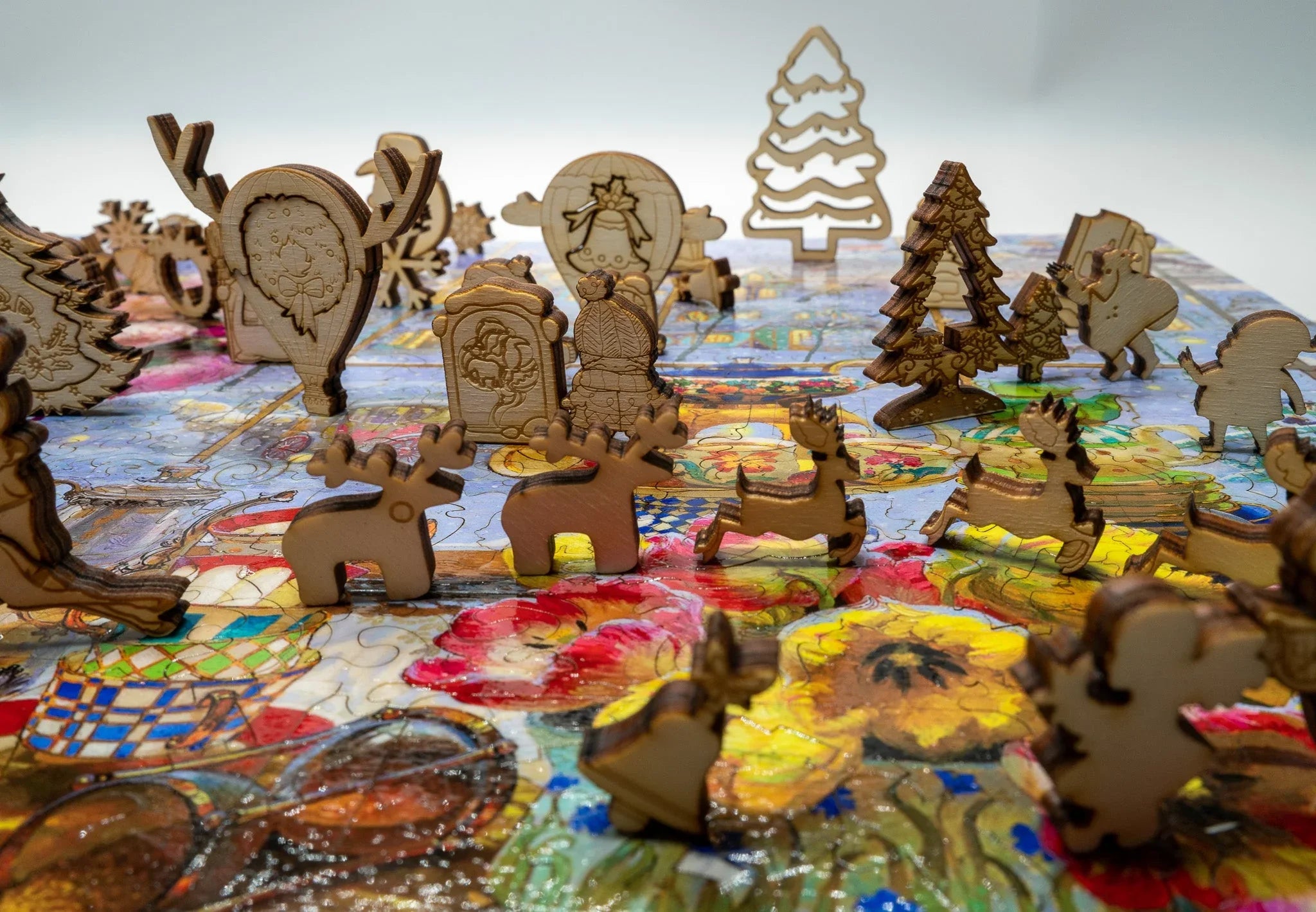 Wooden Christmas puzzle pieces shaped as reindeer, trees, and ornaments on a colorful puzzle base