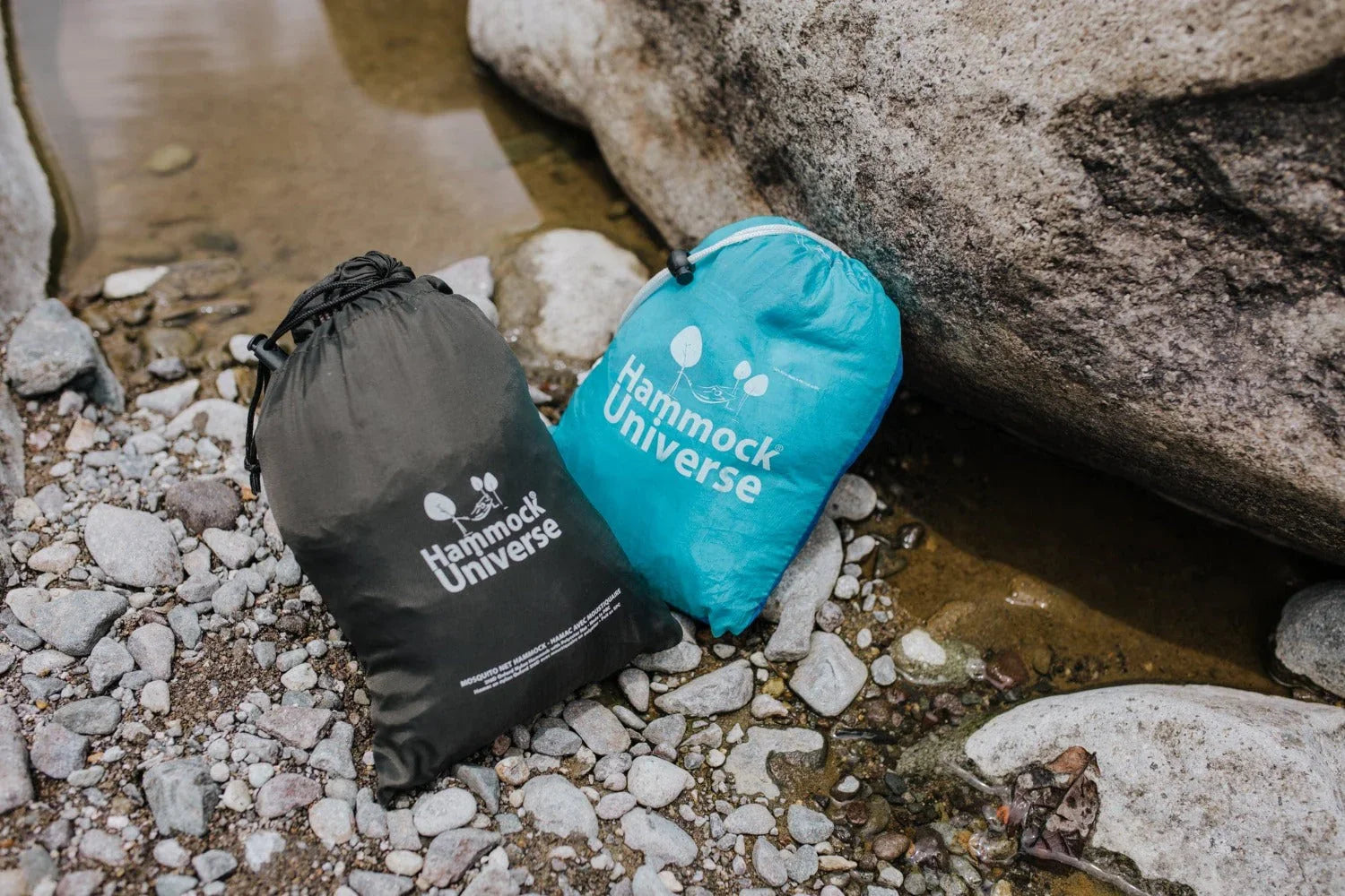 Hammock Universe stuff sacks outdoor by river rocks, camping gear, travel bags