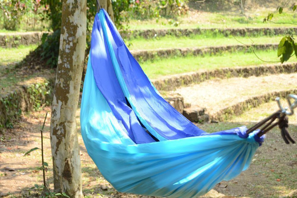 Blue hammock tied to a tree in a sunny outdoor garden setting