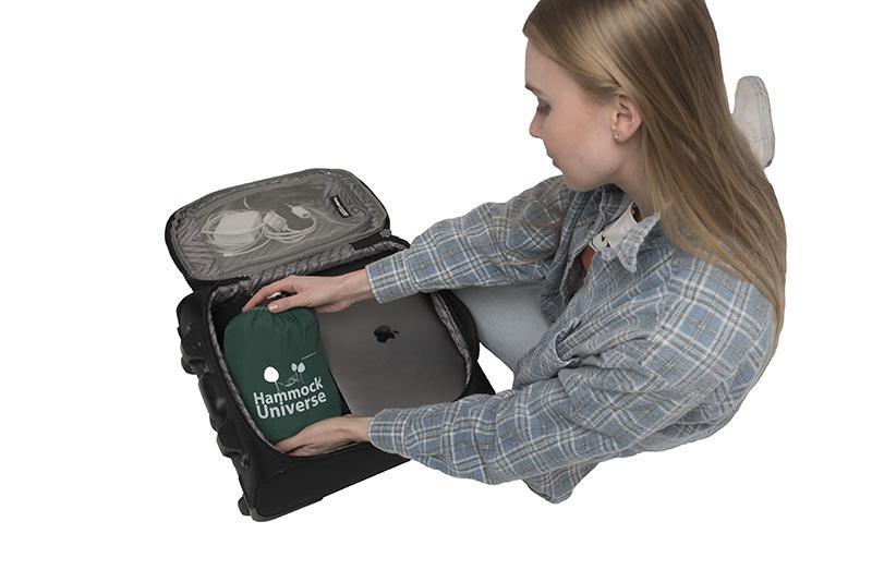 Woman packing Hammock Universe travel hammock and laptop into suitcase