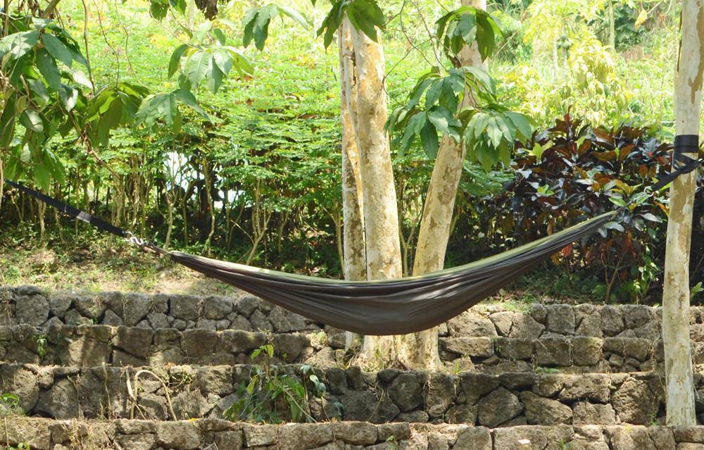 Outdoor hammock tied between trees over stone terrace in lush garden setting