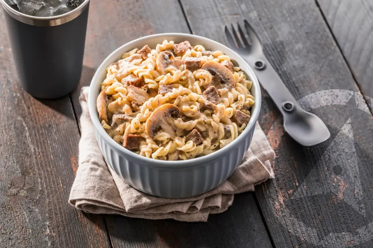Creamy beef stroganoff pasta with mushrooms in a grey bowl on rustic wooden table