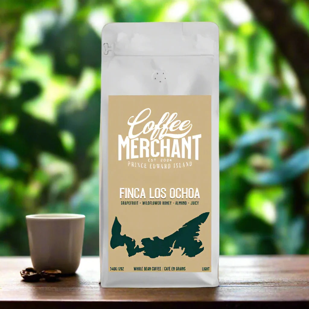 Coffee Merchant Finca Los Ochoa whole bean coffee bag with a cup, on a wooden table outdoors