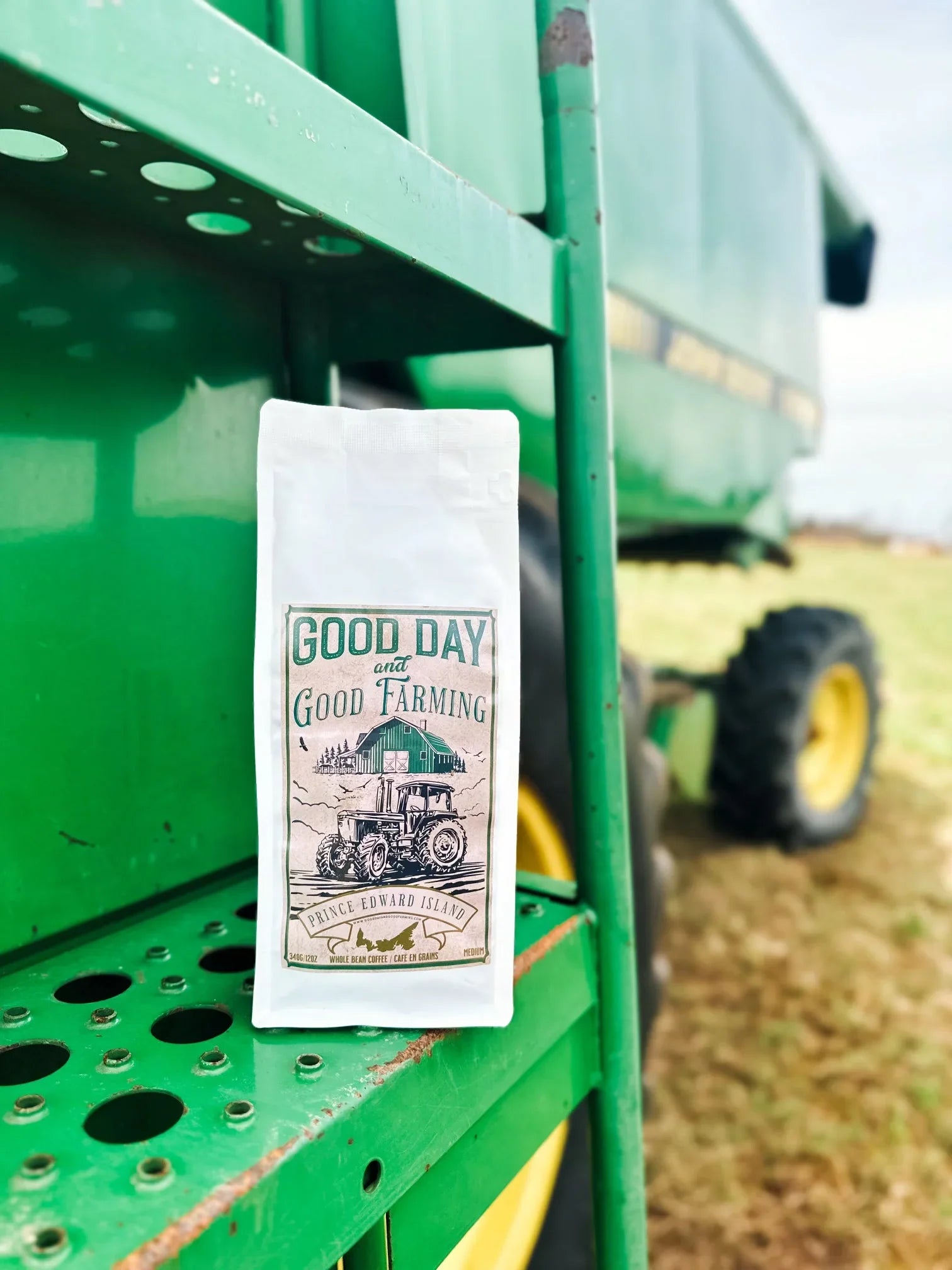 Good Day and Good Farming coffee bag on green tractor outdoors, farm-themed packaging