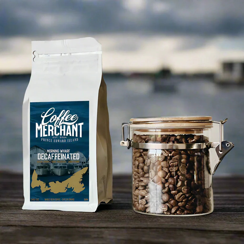 Coffee Merchant Prince Edward Island decaf coffee bag and jar of beans on wood table by water