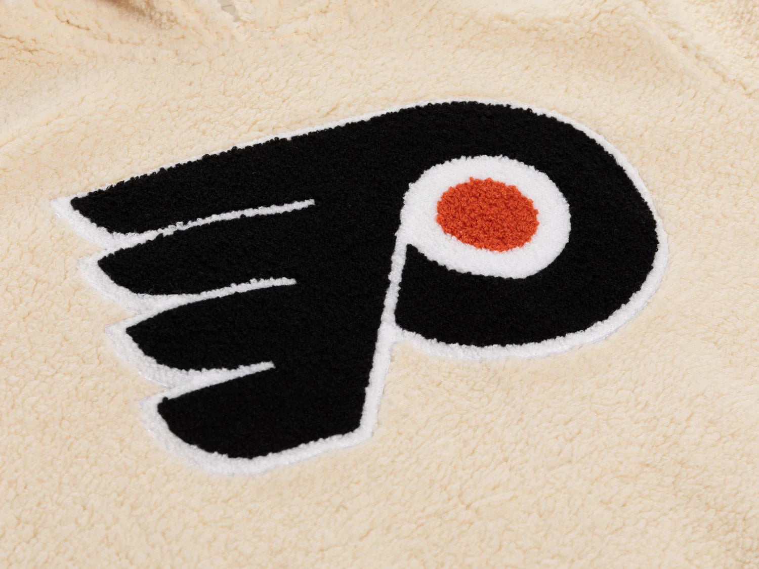 Chenille Flyers logo patch on cream sherpa fleece fabric, hockey team apparel detail