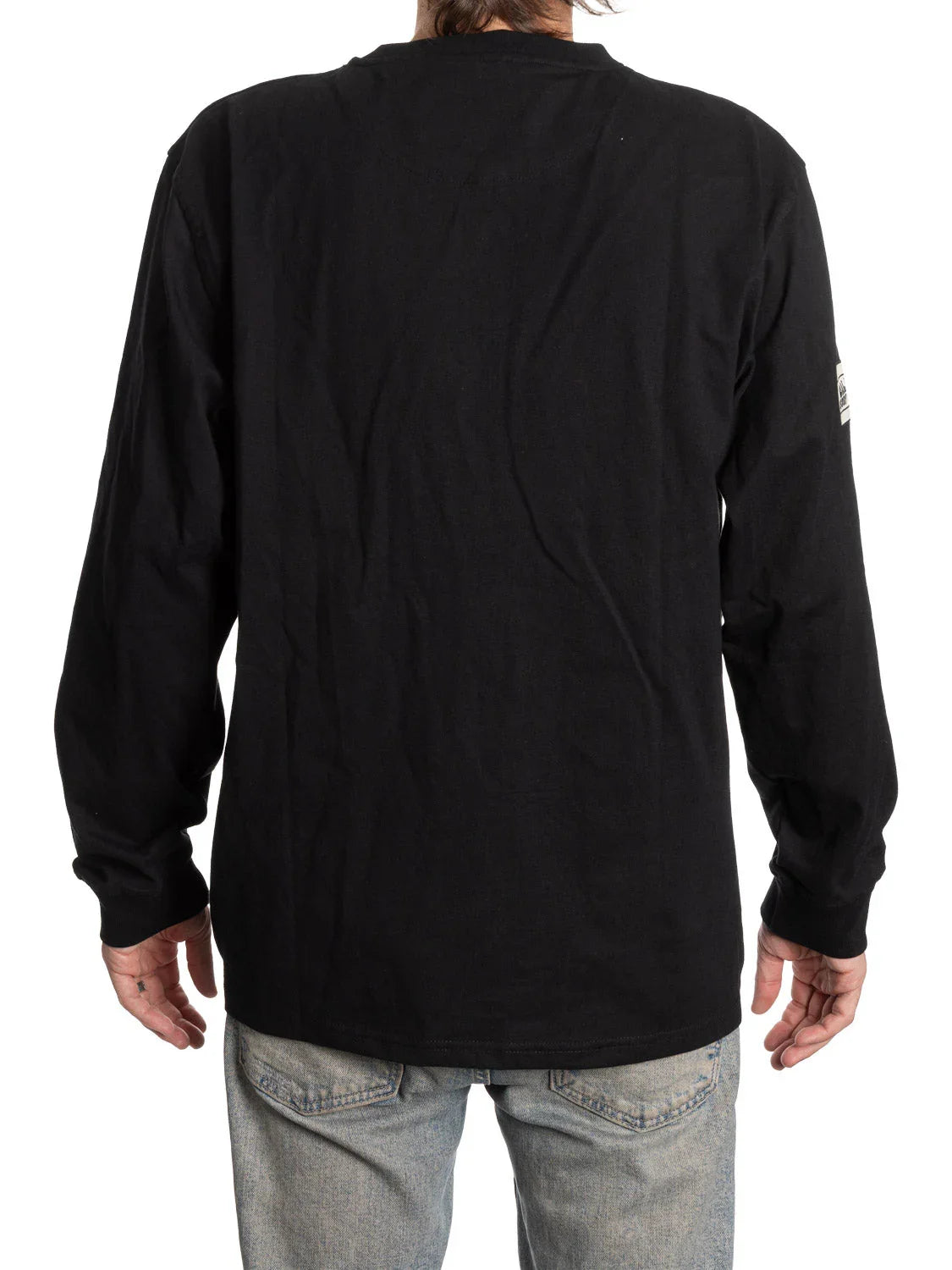 Back view of a black long sleeve Henley shirt with patch detail on sleeve, worn with jeans.
