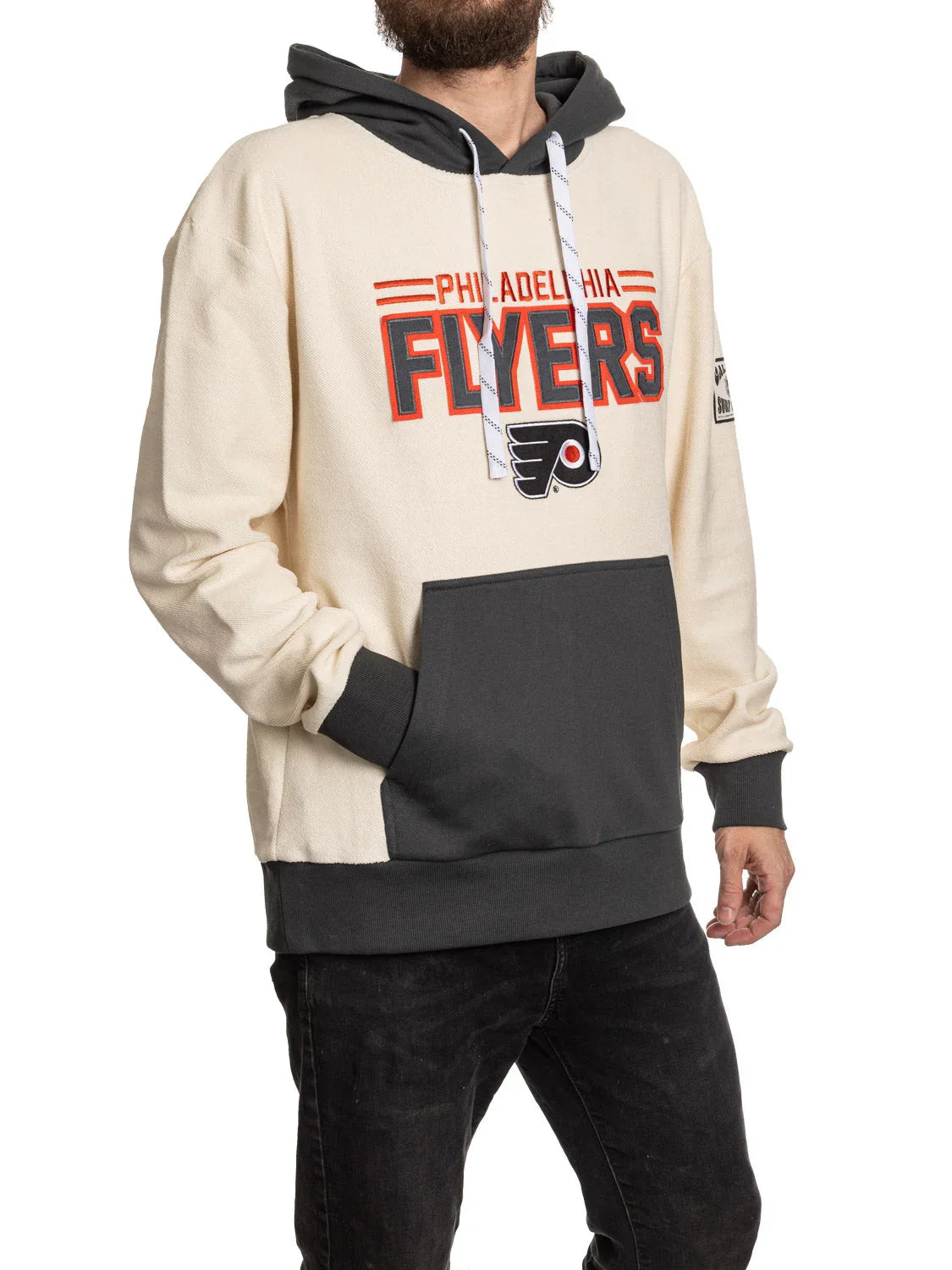 Man wearing Philadelphia Flyers cream and black hoodie with team logo and front pocket