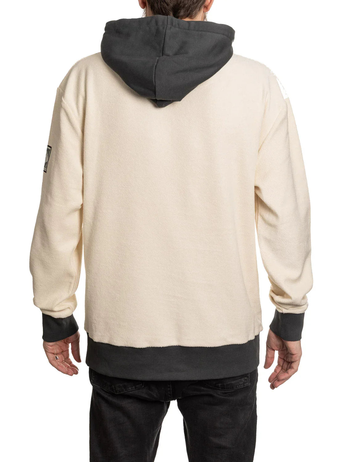 Man wearing beige hoodie with black hood, cuffs, and hem, viewed from the back