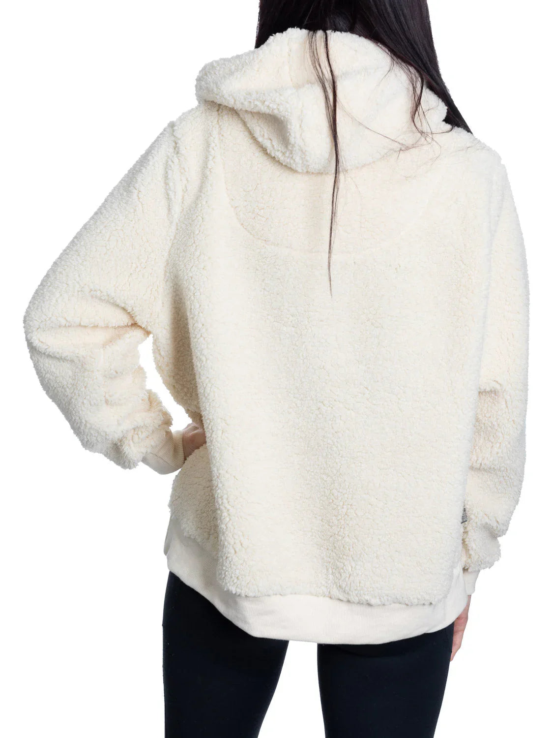 Back view of woman wearing cream sherpa hoodie and black leggings, white background