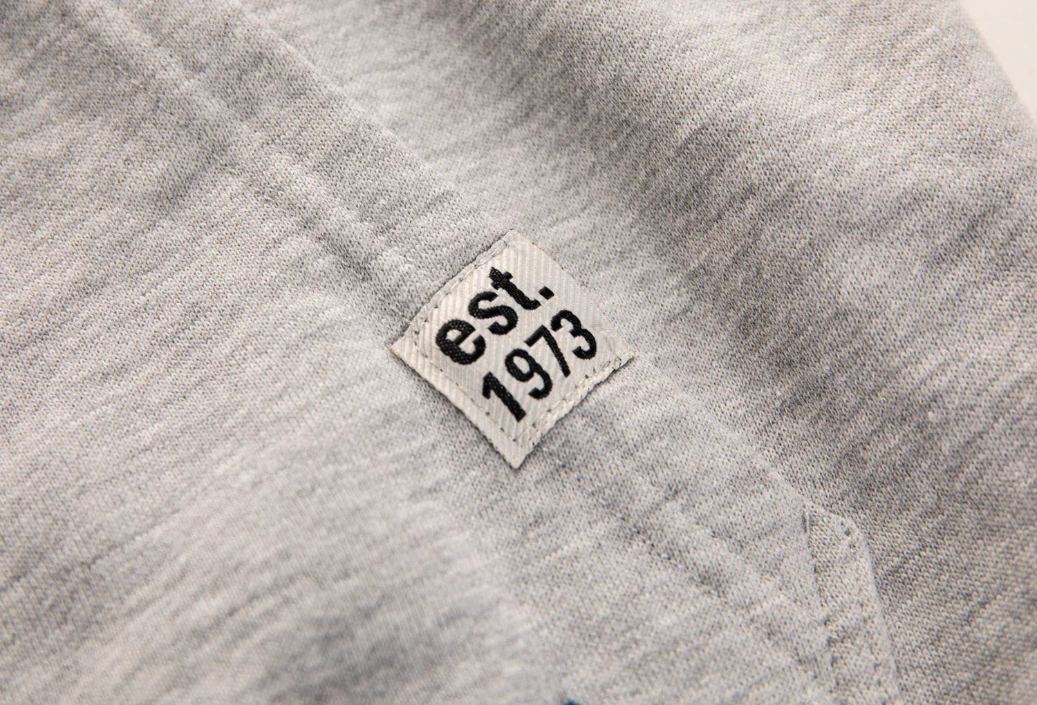 Gray t-shirt close-up with est. 1973 woven tag on seam