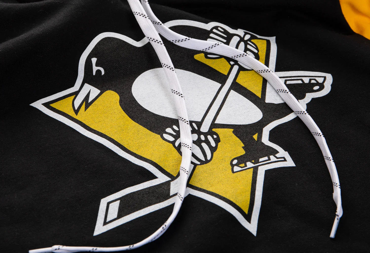 Close-up of Pittsburgh Penguins hockey logo on black hoodie with white drawstrings