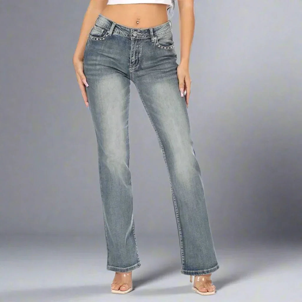 Woman wearing high-waisted straight leg blue jeans on gray background