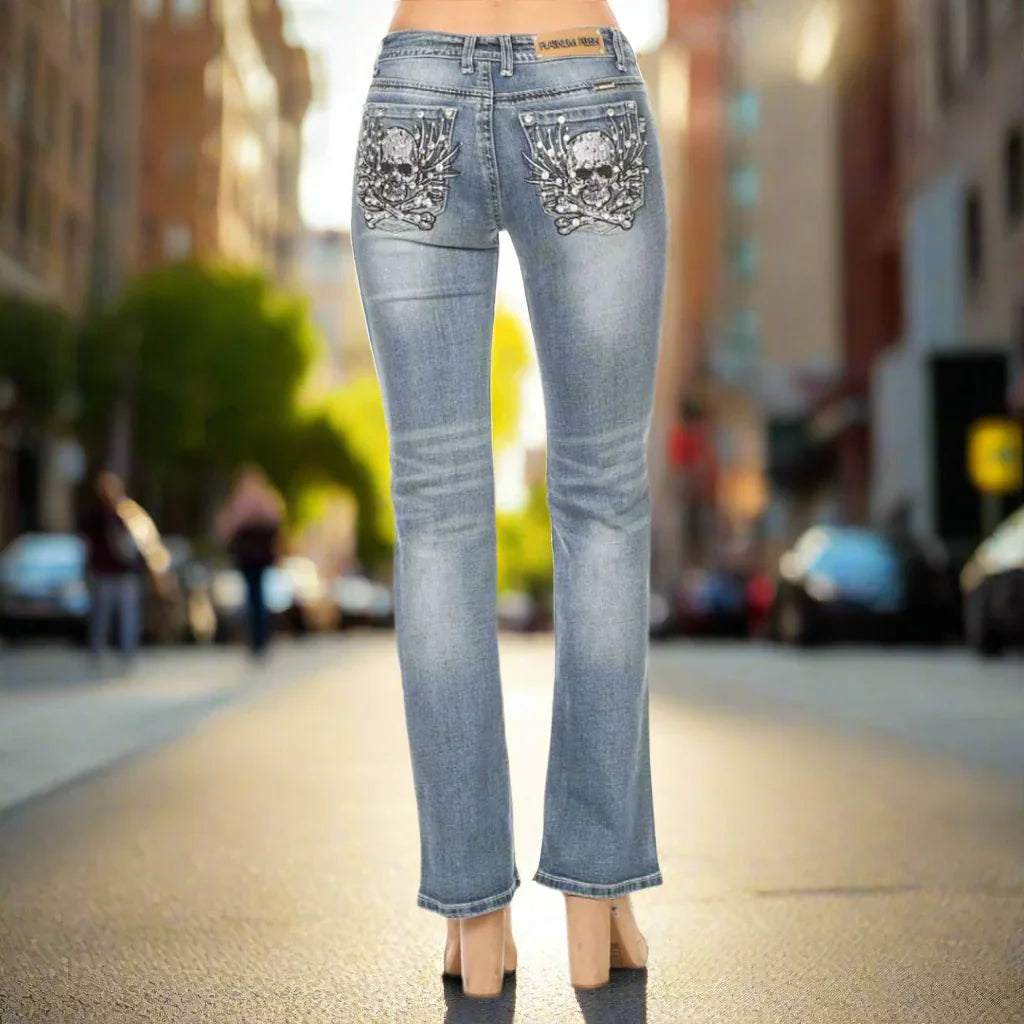 Woman in light blue jeans with skull embroidery back pockets standing on city street