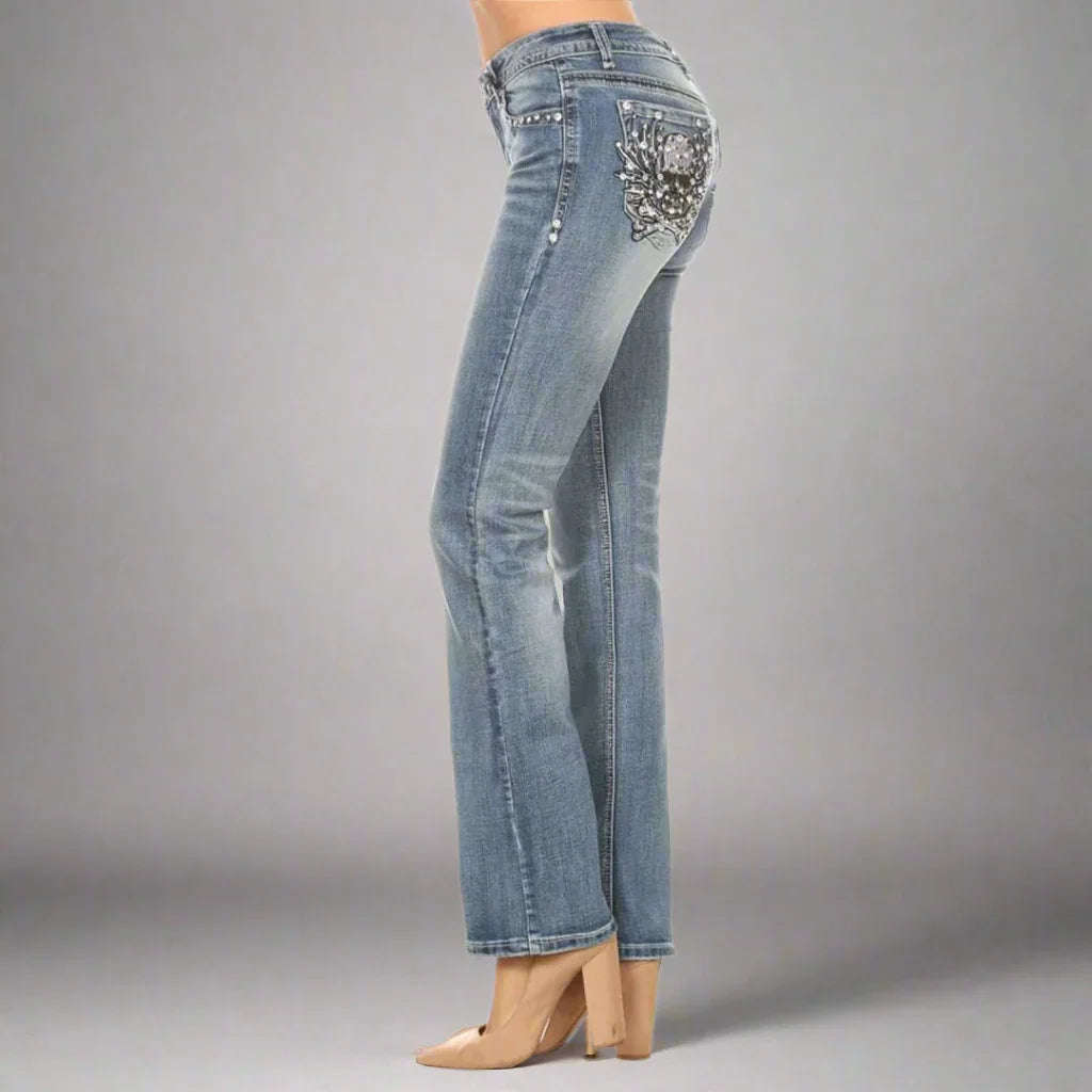 Women's light wash bootcut jeans with embellished back pocket, side view, studio lighting