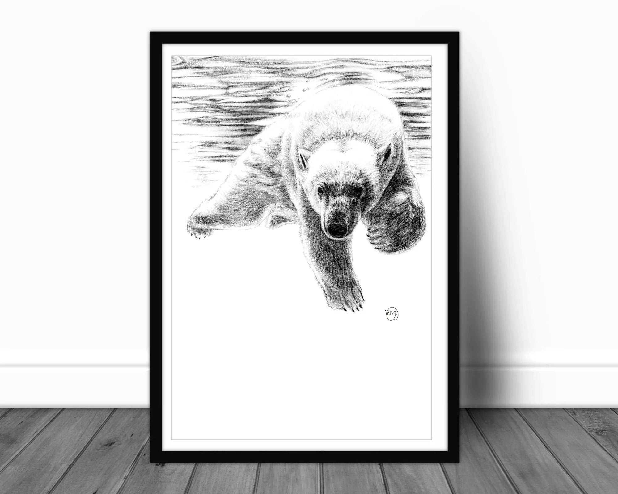 Framed black and white drawing of a polar bear swimming, displayed on a wooden floor.