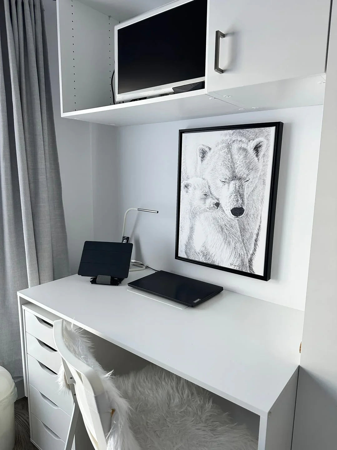 Black and white polar bear with cub illustration on wall in minimalist white desk setup
