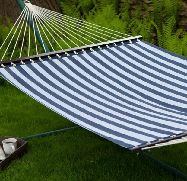 Blue and white striped hammock on green grass with ferns in background, outdoor relaxing spot