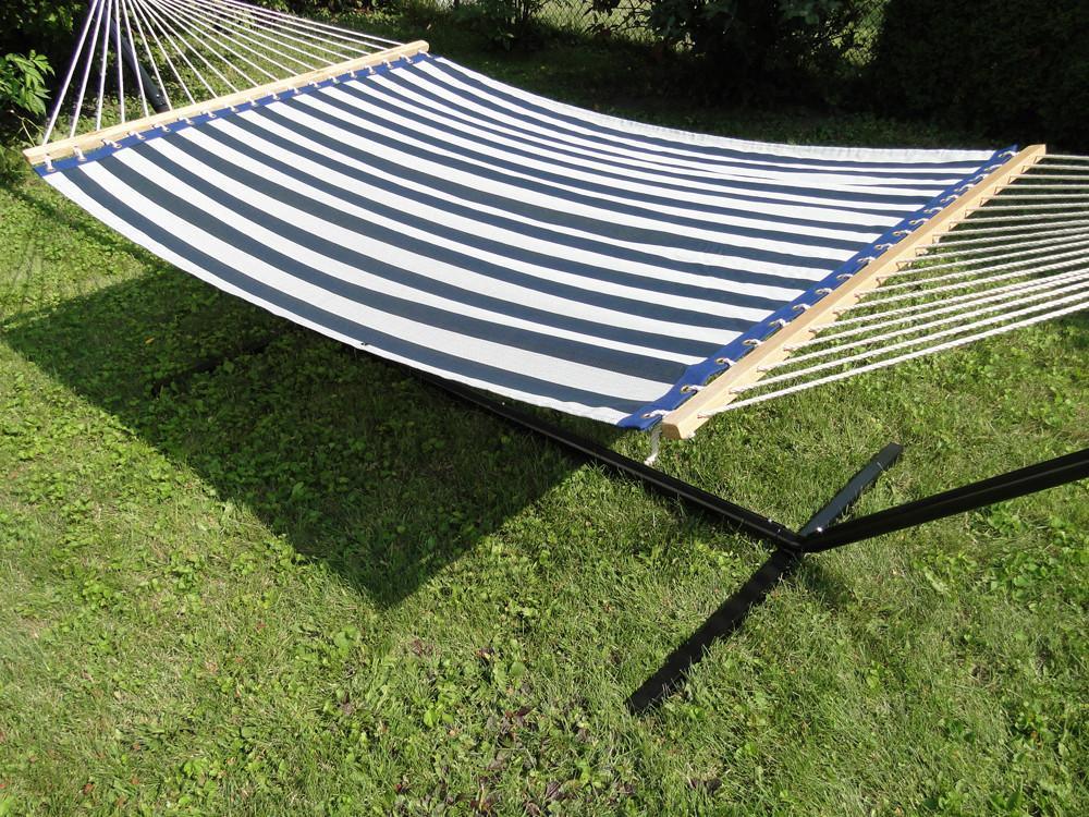 Blue and white striped hammock on stand outdoors on green grass lawn
