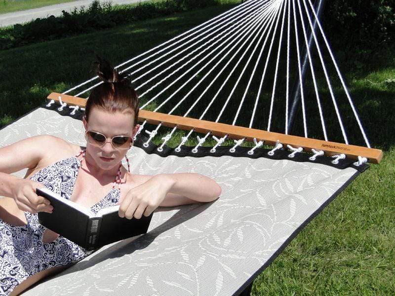 Woman in sunglasses relaxing on outdoor hammock reading a book in the sun